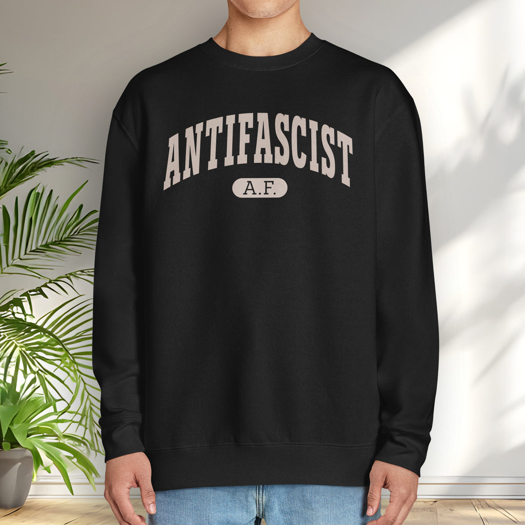Male model wearing black crewneck sweatshirt with varsity collegiate style text across the front that reads "Antifascist AF."