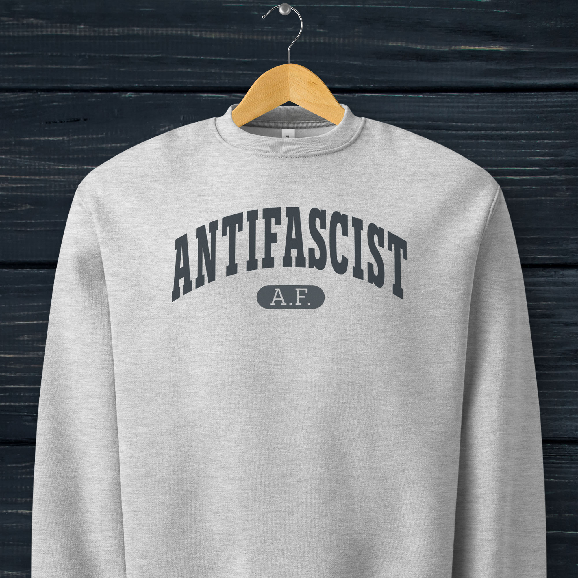 Hanging grey Bella + Canvas heavyweight crewneck sweatshirt with varsity collegiate style text across the front that reads "Antifascist AF."