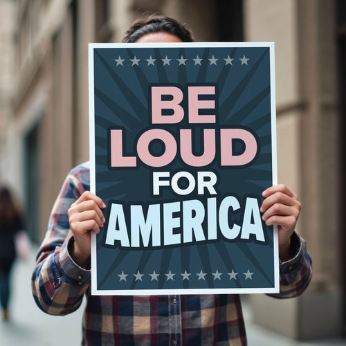 Person holding protest sign with text “Be Loud for America” in patriotic colors.