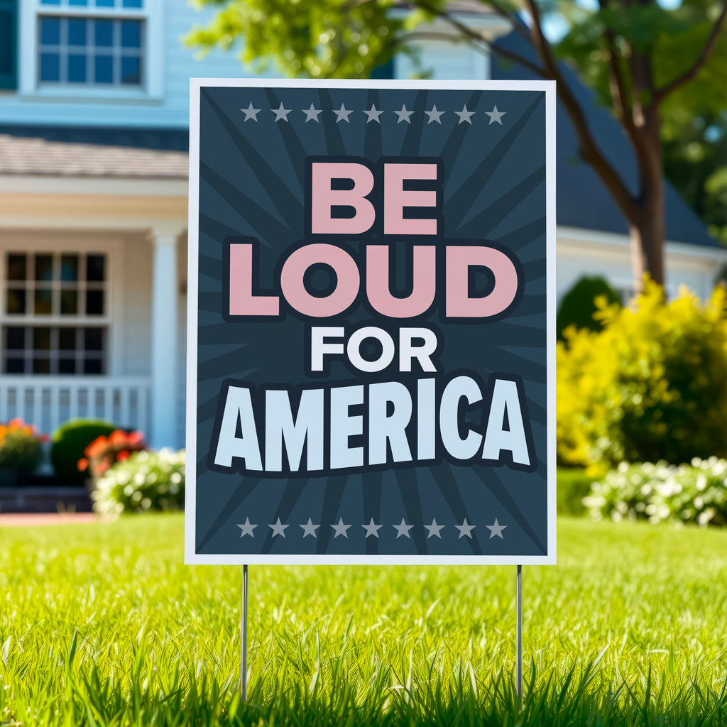 Yard sign with text “Be Loud for America” in patriotic colors, planted in green lawn.