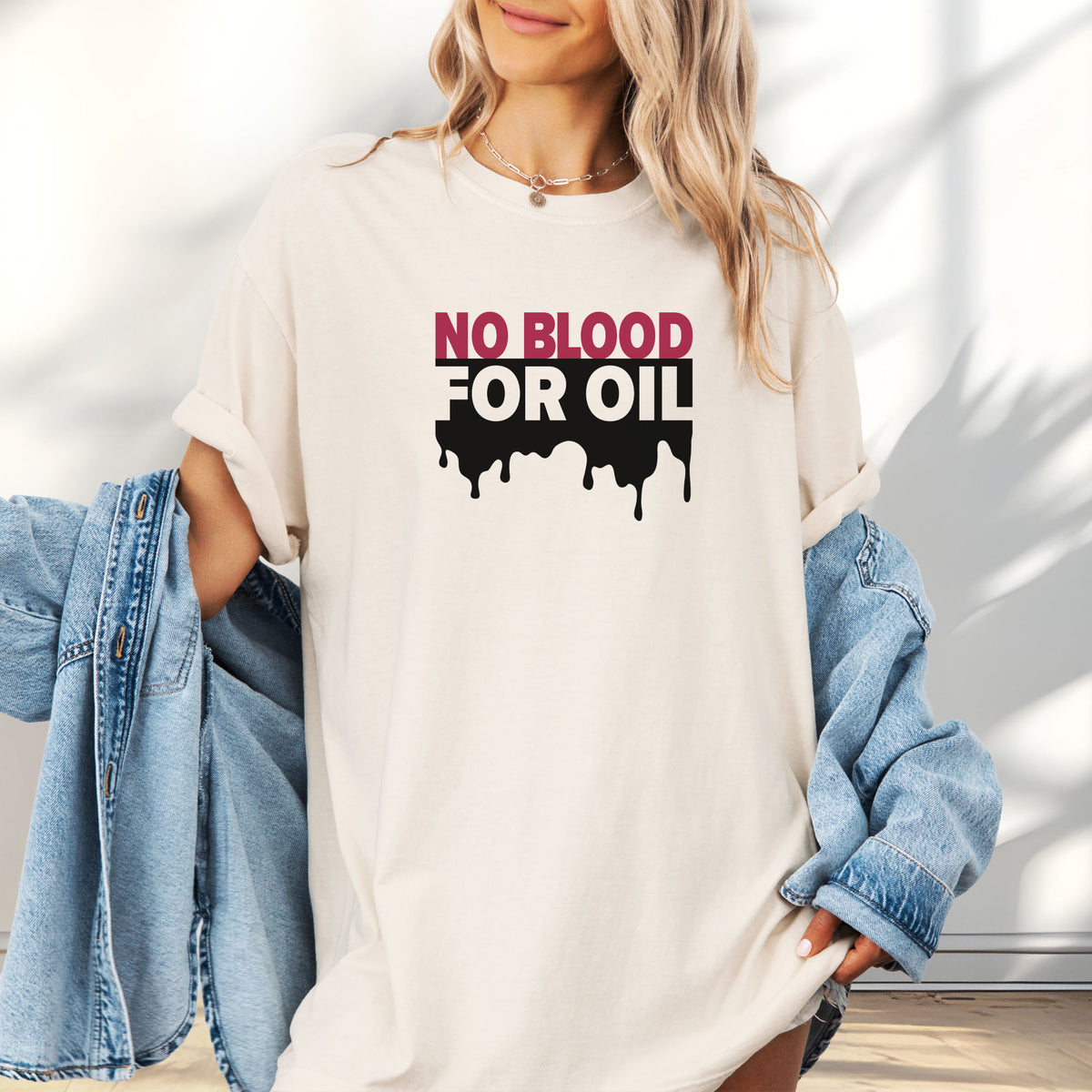 Female model wearing oversized ivory protest t-shirt with bold text reading “No Blood for Oil” and dripping oil graphic, anti-war political shirt.