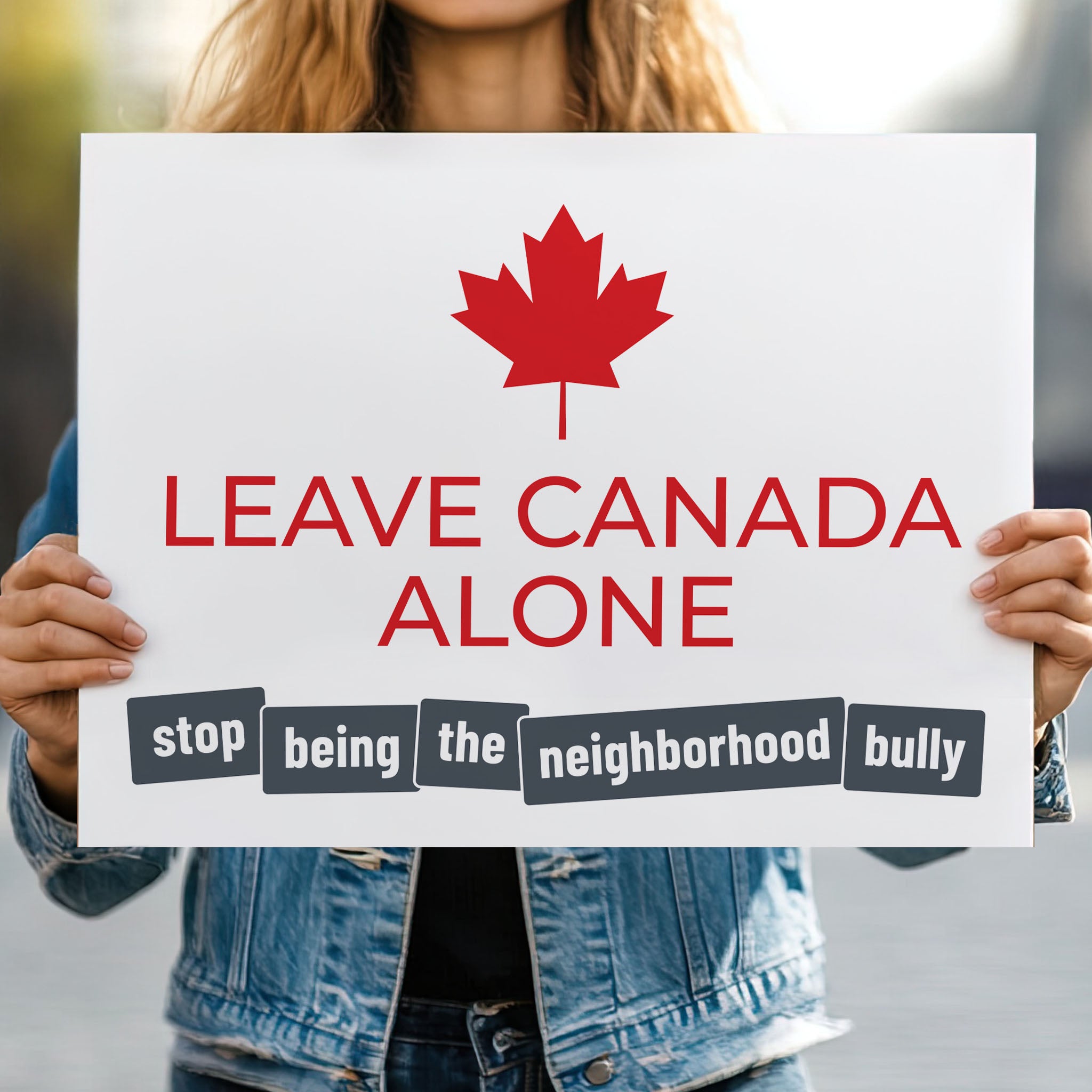 Person holding protest sign with strong red text: "Leave Canada Along" and smaller grey text: "Stop being the neighborhood bully" to directly call out of Trump foreign and tariff policy.