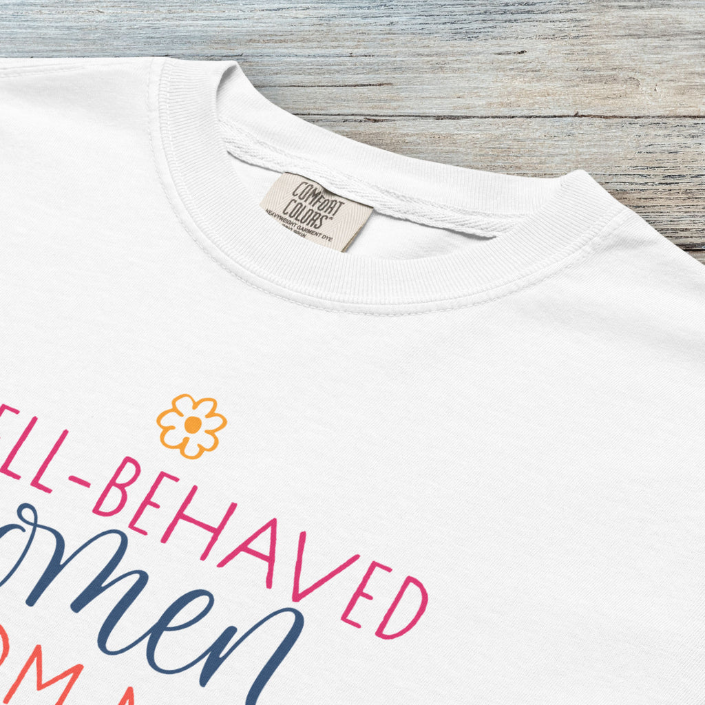 Closeup detail of white feminist t-shirt with colorful text that reads “Well-behaved women seldom make history” — empowering women’s rights shirt and activist apparel.