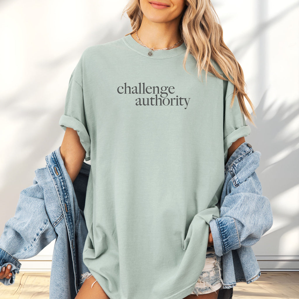 Female model wearing oversized bay t-shirt with minimalist serif text block reading “challenge authority."