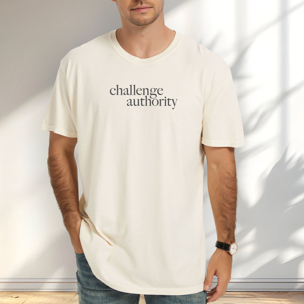 Male model wearing ivory t-shirt with minimalist serif text block reading “challenge authority."