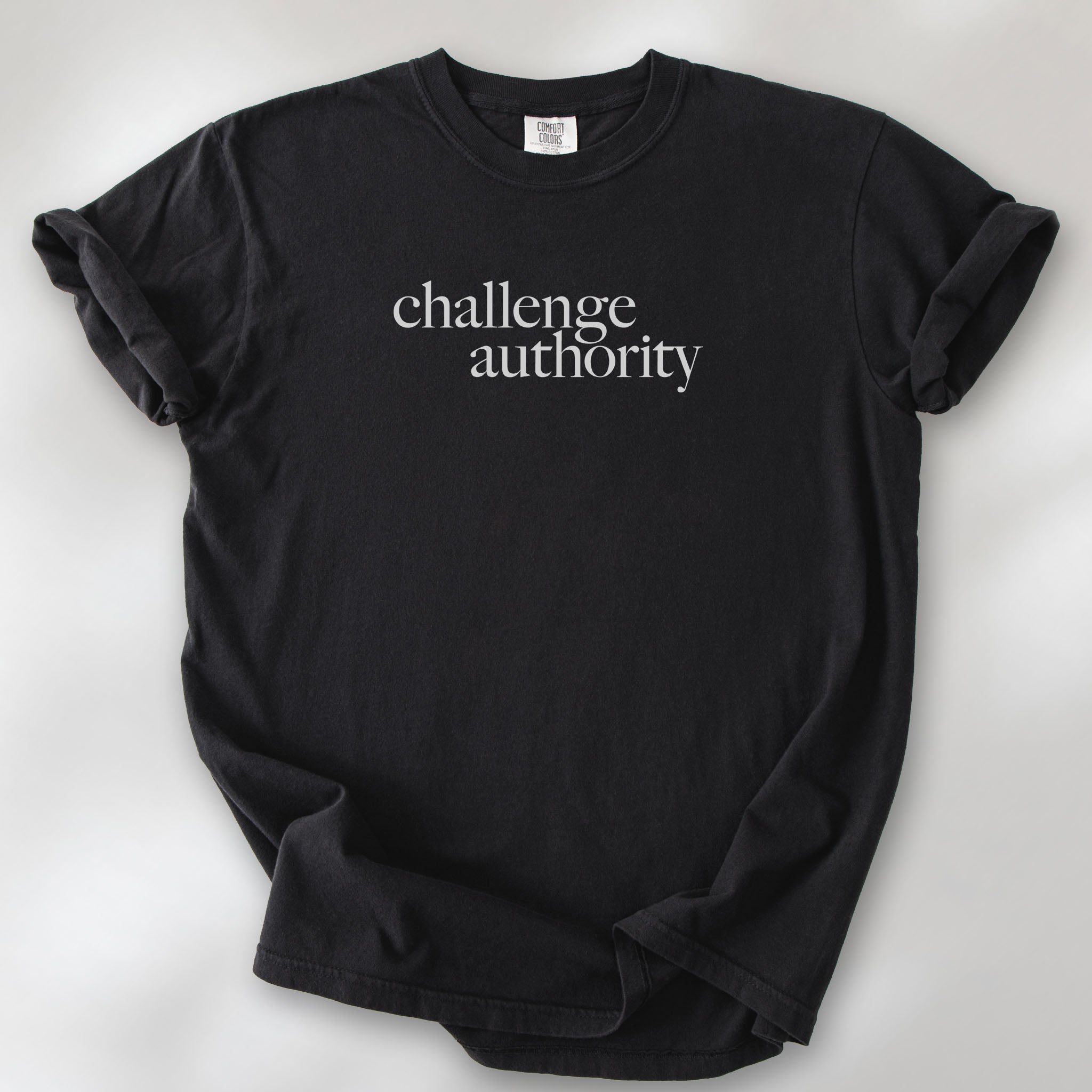 Black t-shirt with minimalist serif text block reading “challenge authority."