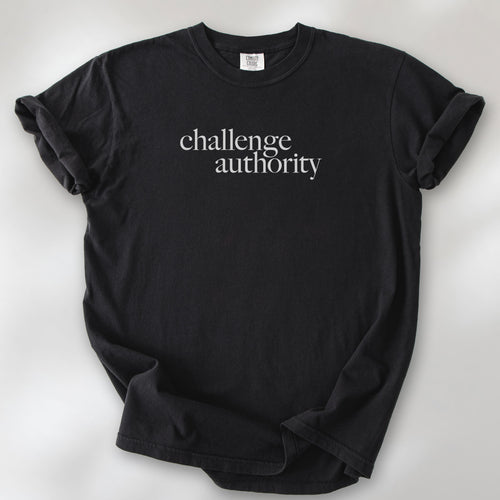 Black t-shirt with minimalist serif text block reading “challenge authority."