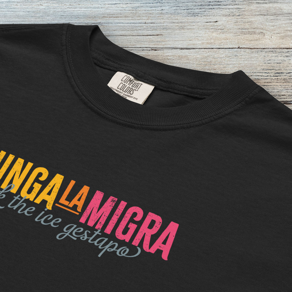 Closeup detail of black t-shirt with brightly colored text that reads "chinga la migra", with subtle script text below that says "fuck the ice gestapo."