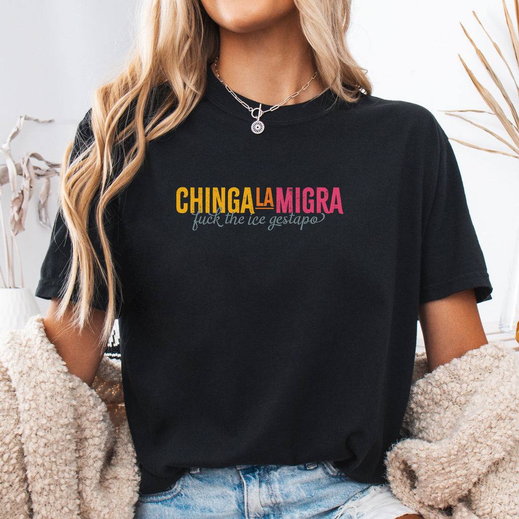 Female mode wearing black t-shirt with brightly colored text that reads "chinga la migra", with subtle script text below that says "fuck the ice gestapo."