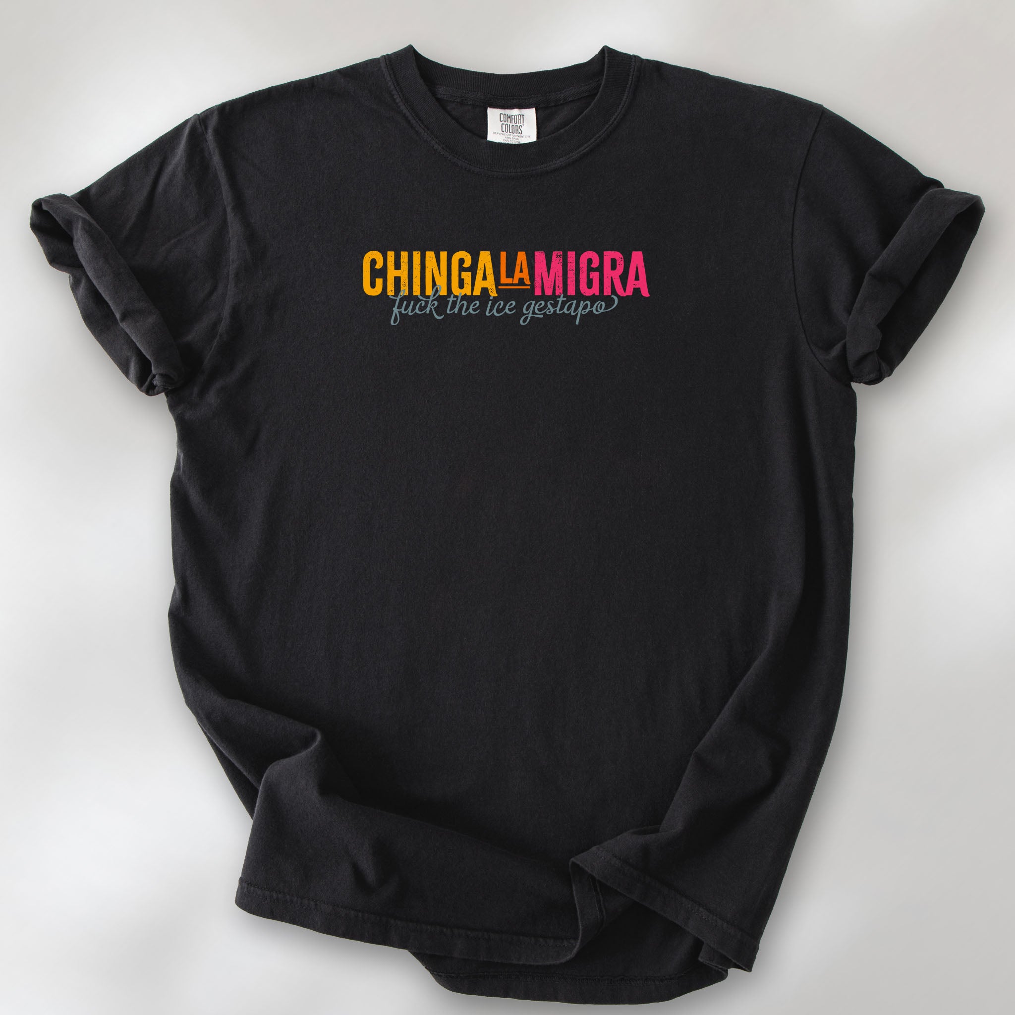 Black t-shirt with brightly colored text that reads "chinga la migra", with subtle script text below that says "fuck the ice gestapo."