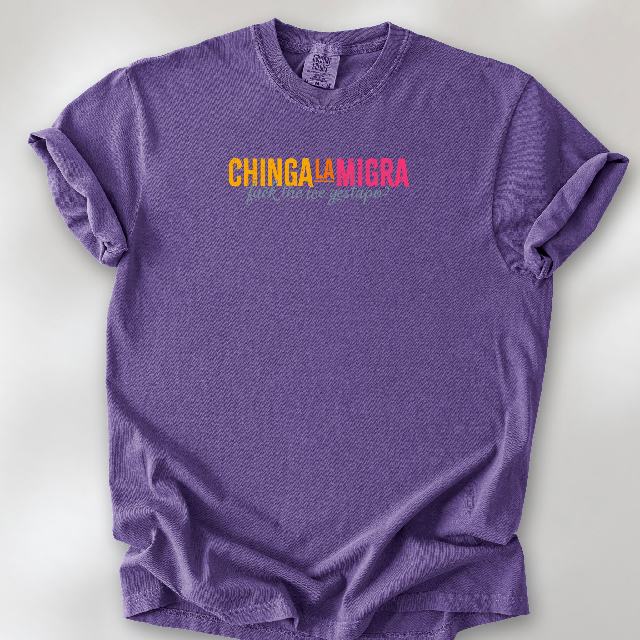 Denim t-shirt with brightly colored text that reads "chinga la migra", with subtle script text below that says "fuck the ice gestapo."