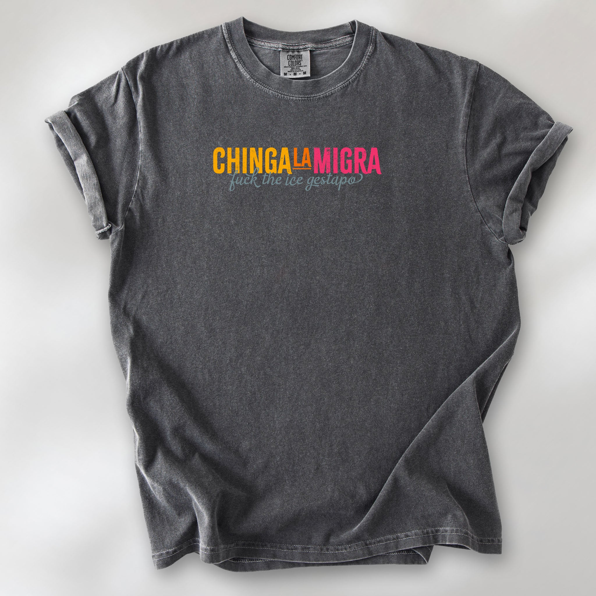Pepper t-shirt with brightly colored text that reads "chinga la migra", with subtle script text below that says "fuck the ice gestapo."