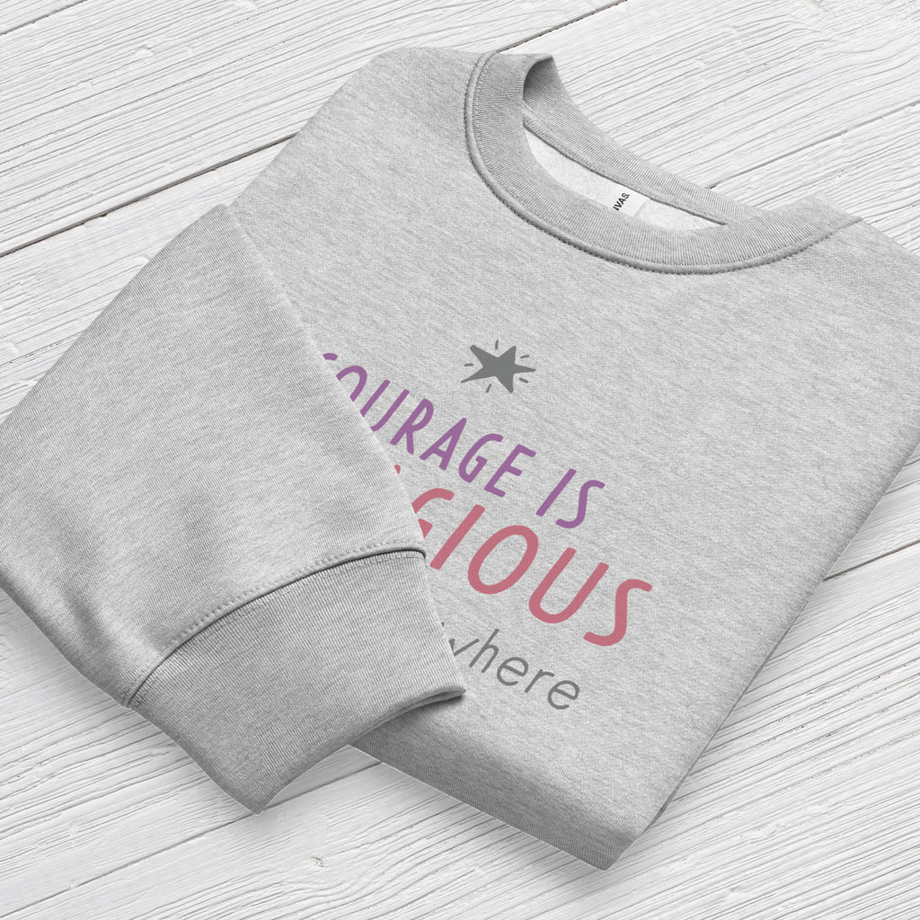 Athletic heather grey crewneck sweatshirt with minimalist stylized text that reads "courage is contagious – spread it everywhere" folded showing neck and sleeve cuff.