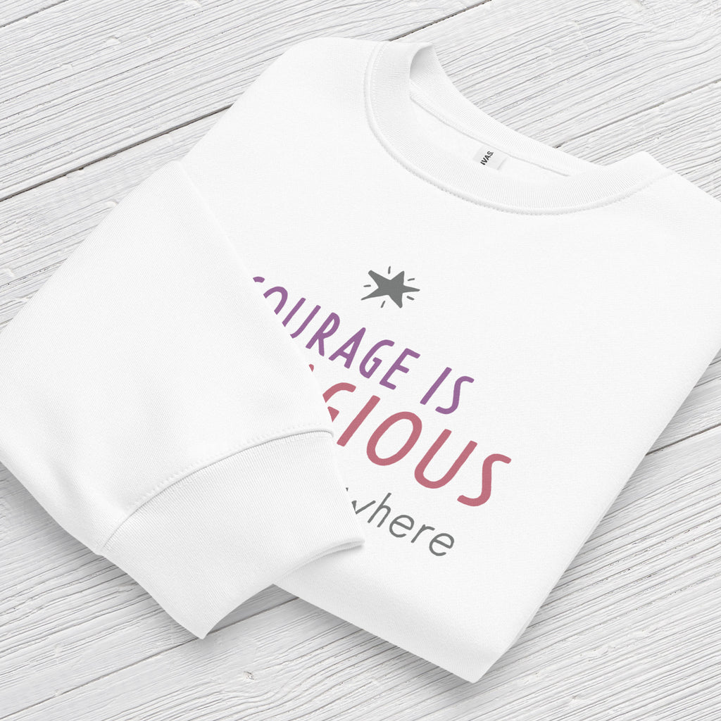 White crewneck sweatshirt with minimalist stylized text that reads "courage is contagious – spread it everywhere" folded showing neck and sleeve cuff.