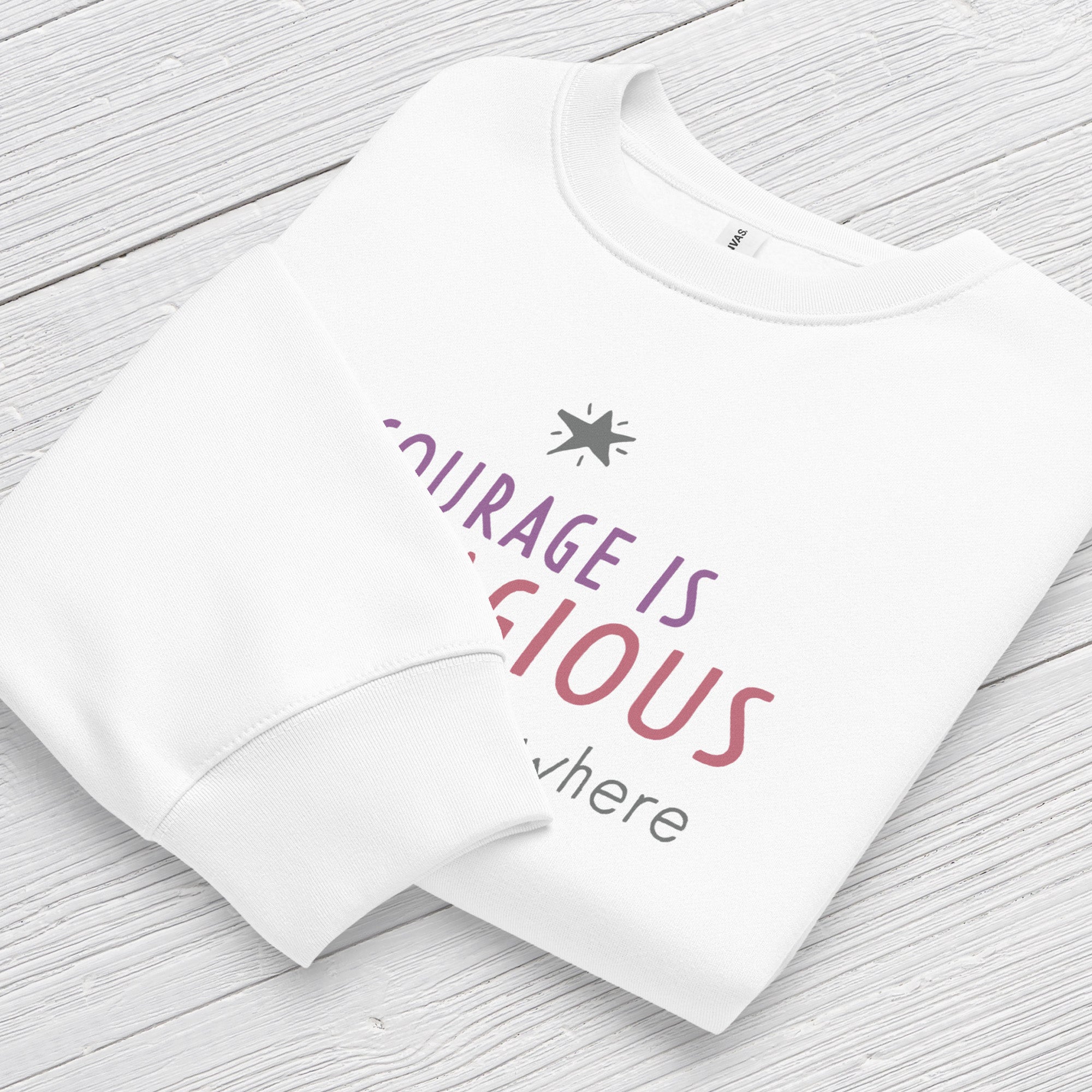 White crewneck sweatshirt with minimalist stylized text that reads "courage is contagious – spread it everywhere" folded showing neck and sleeve cuff.
