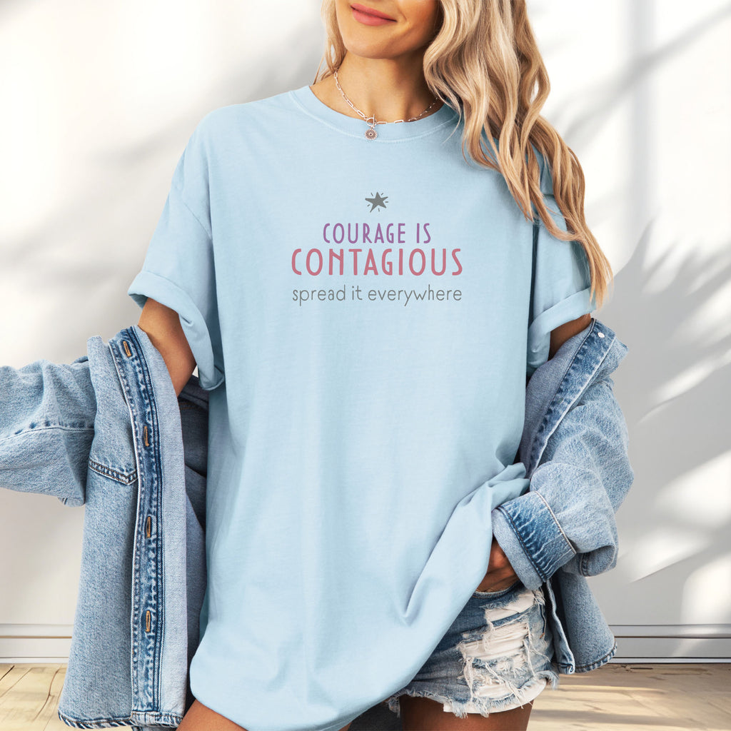 Female model wearing oversized chambray t-shirt with the words “Courage Is Contagious – Spread It Everywhere” printed in soft purple, red, and gray.