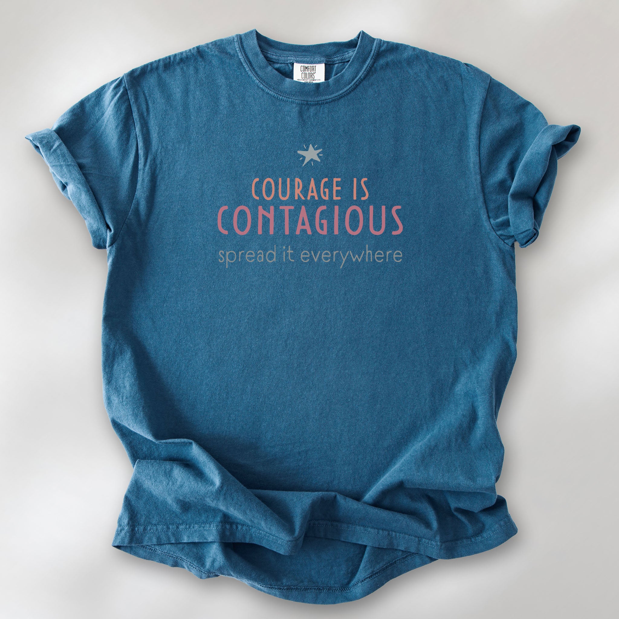 Midnight t-shirt with the words “Courage Is Contagious – Spread It Everywhere” printed in soft pink, coral, and gray.