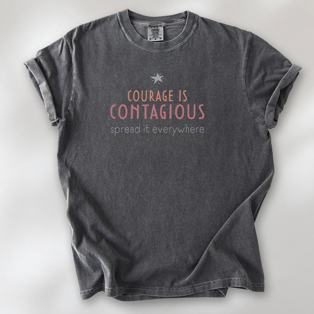 Pepper t-shirt with the words “Courage Is Contagious – Spread It Everywhere” printed in soft pink, coral, and gray.
