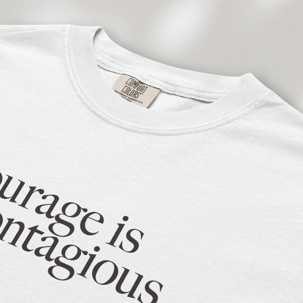 Closeup detail of white t-shirt with minimalist serif text reading “courage is contagious”.