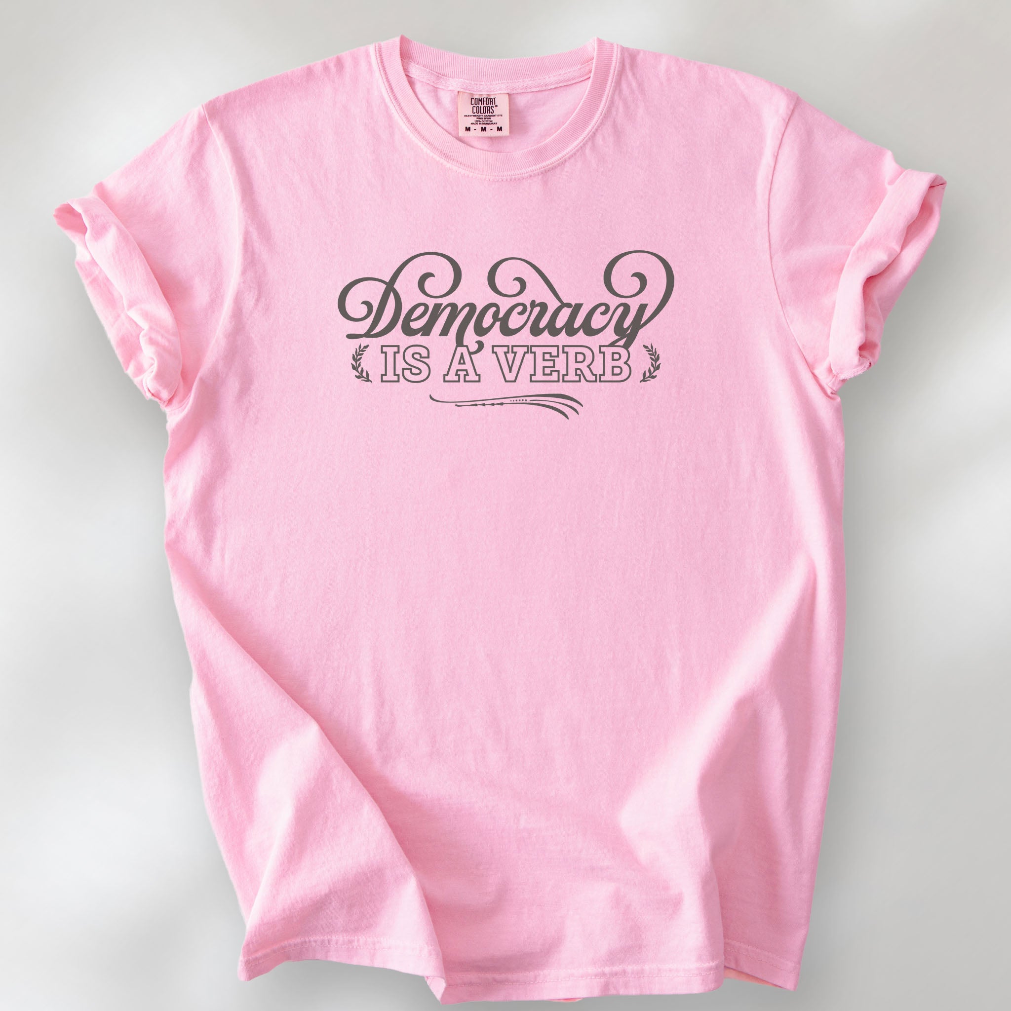 Blossom t-shirt with the phrase “Democracy Is a Verb” in decorative mint green lettering.