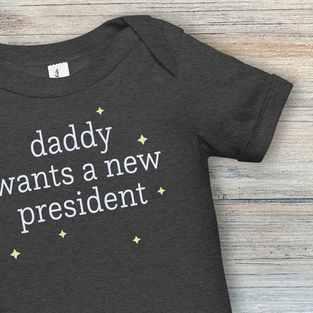 Closeup of neckline and sleeves of dark grey heather baby short sleeve one piece with white text reading “daddy wants a new president."