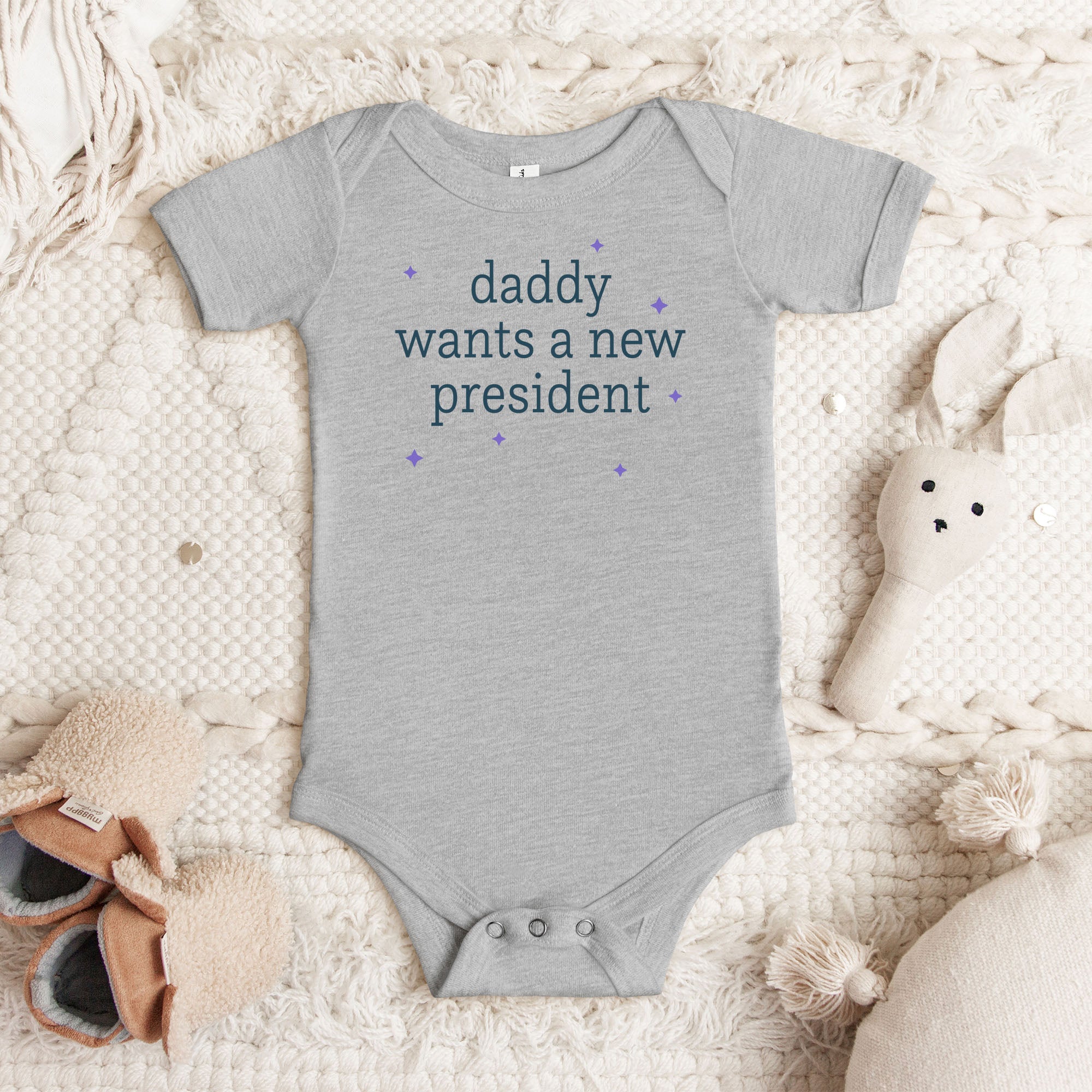 Grey baby short sleeve one piece with dark text reading “mommy wants a new president."
