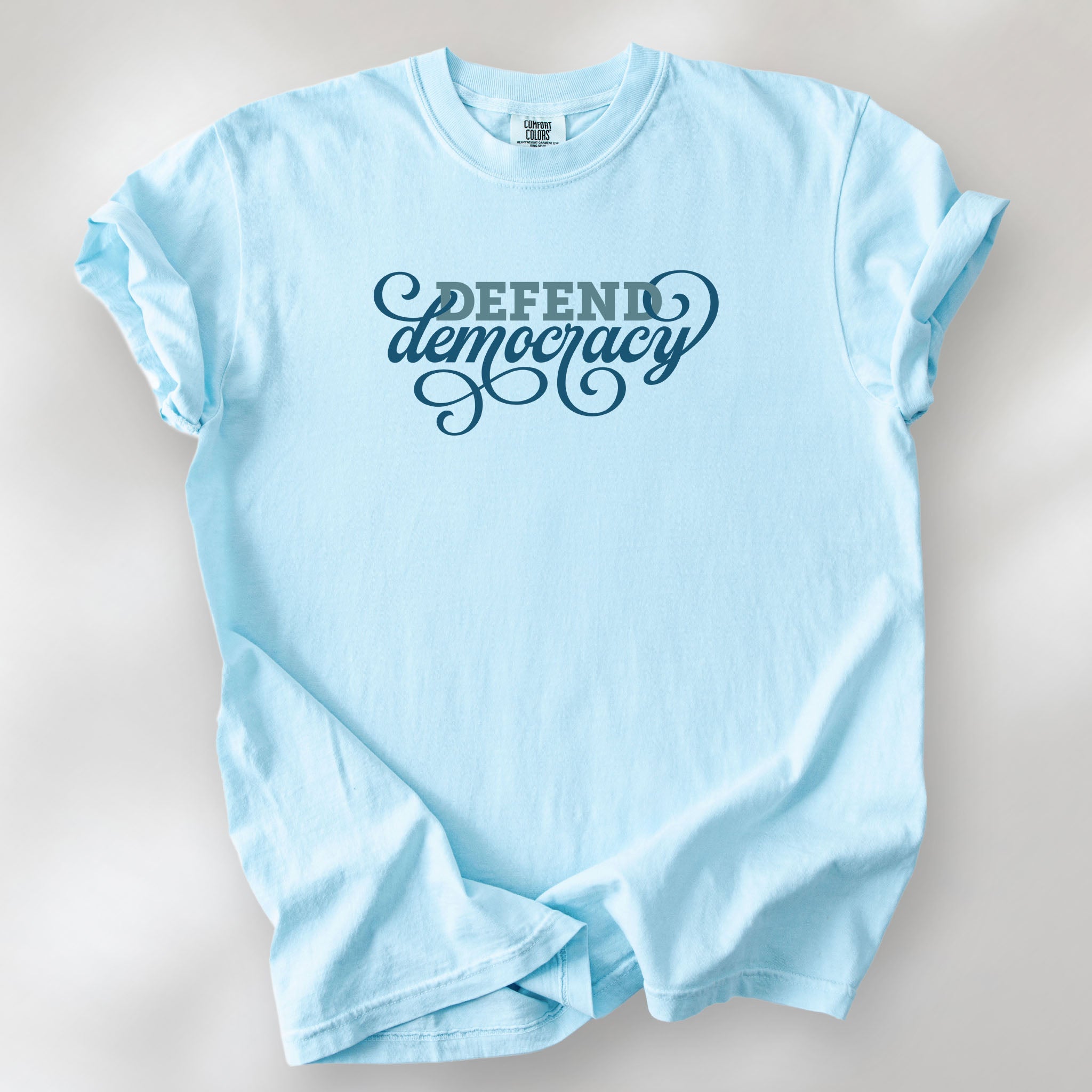 Chambray t-shirt with blue slab and script text reading “Defend Democracy.”