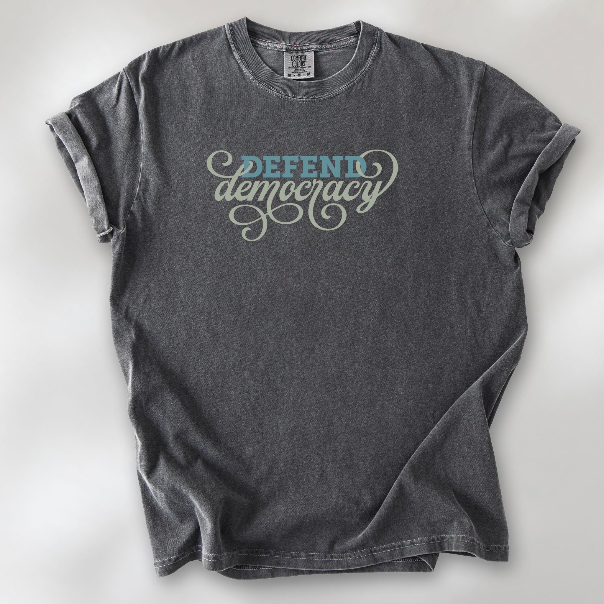 Pepper t-shirt with blue and green script text reading “Defend Democracy.”