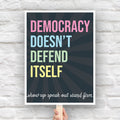 Downloadable, printable protest sign with dark background with subtle burst, bold colorful text that reads "democracy doesn't defend itself", then white script text near the bottom that reads "show up, speak out, stand firm."