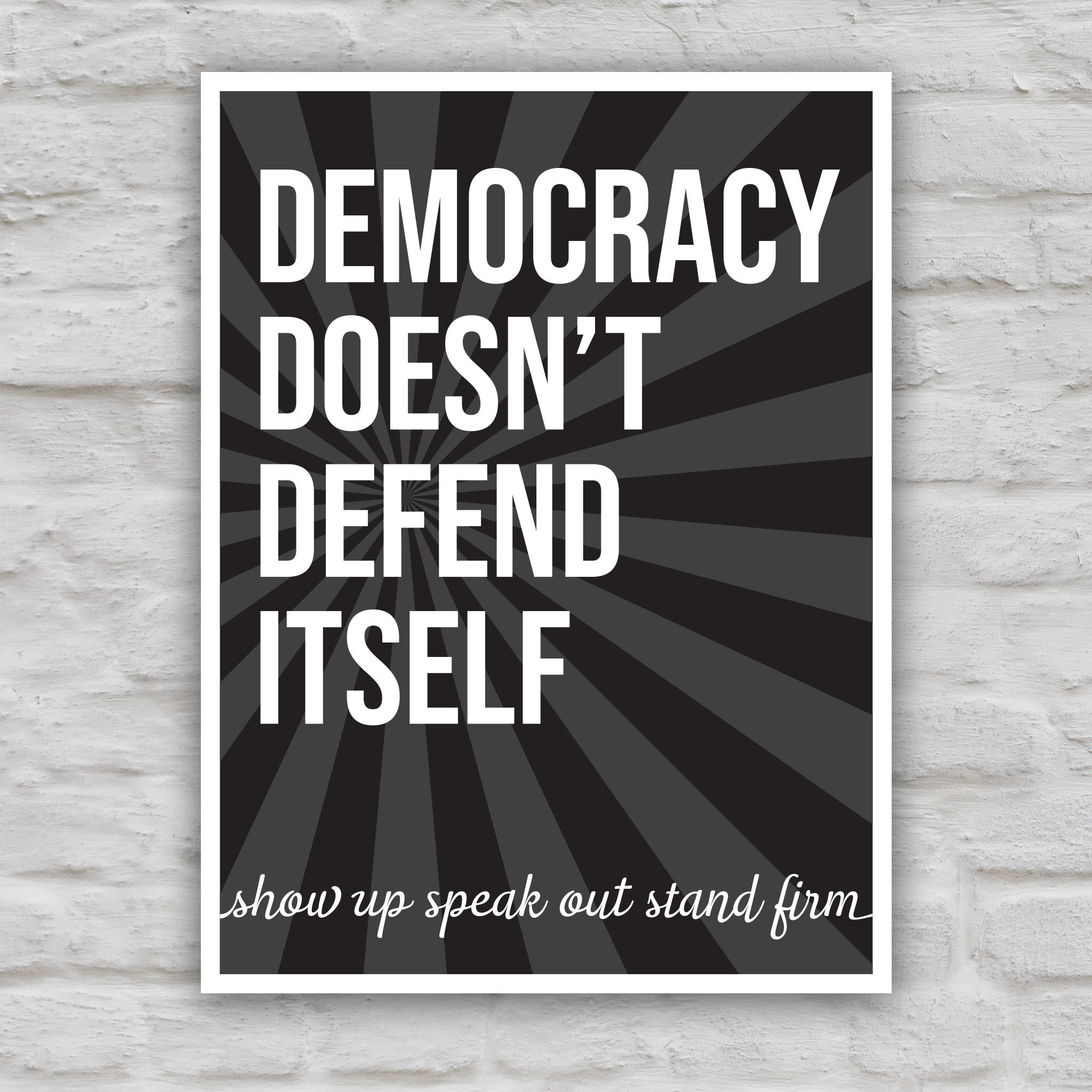Black and white version of protest sign with dark background with subtle burst, bold text that reads "democracy doesn't defend itself", then white script text near the bottom that reads "show up, speak out, stand firm."