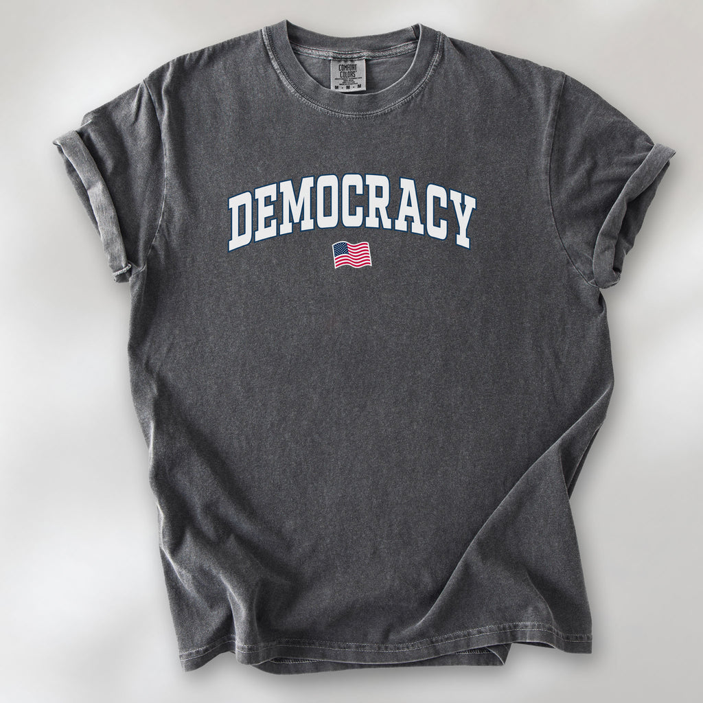 Pepper t-shirt with varsity-style graphic that says "democracy" with a USA flag beneath it.