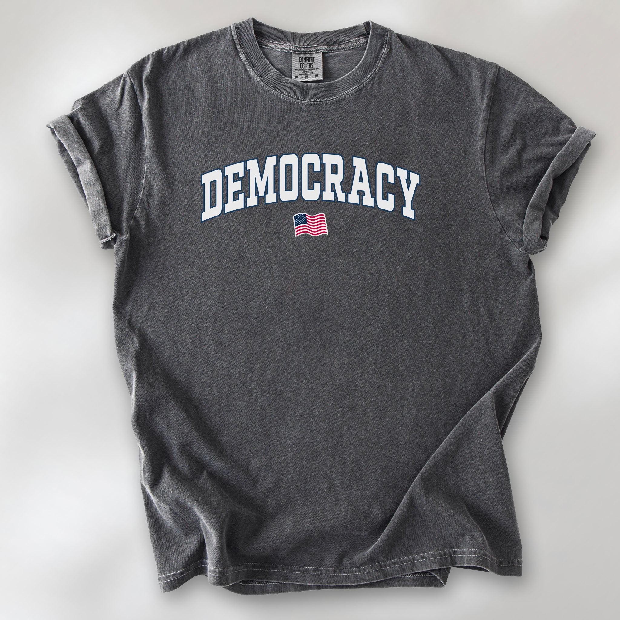 Pepper t-shirt with varsity-style graphic that says "democracy" with a USA flag beneath it.