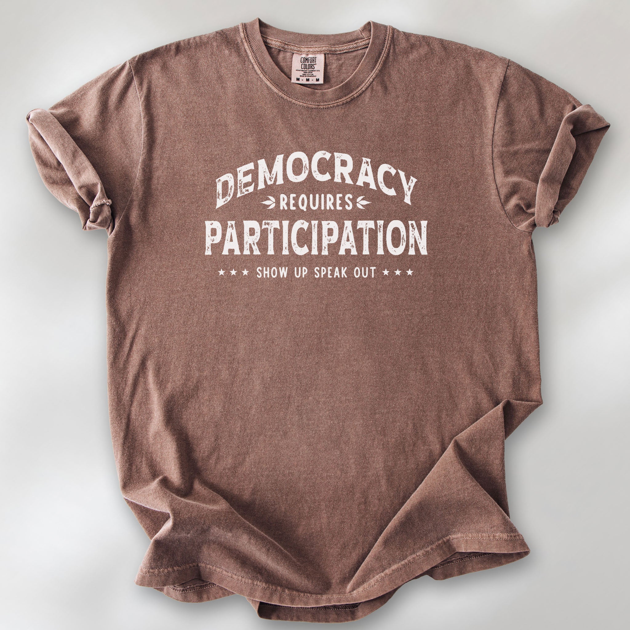 Espresso t-shirt with vintage style typography reading “Democracy Requires Participation — Show Up Speak Out”.