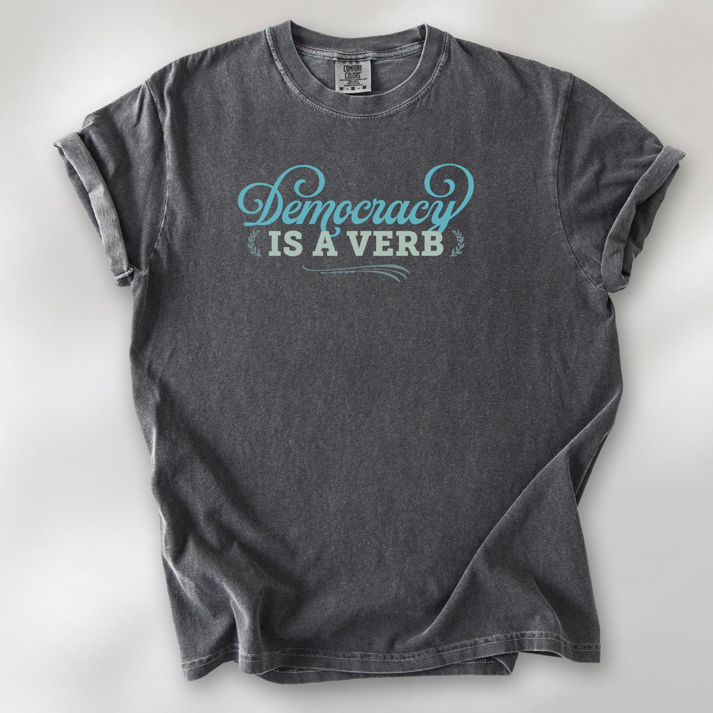 Pepper t-shirt with the phrase “Democracy Is a Verb” in decorative lettering.
