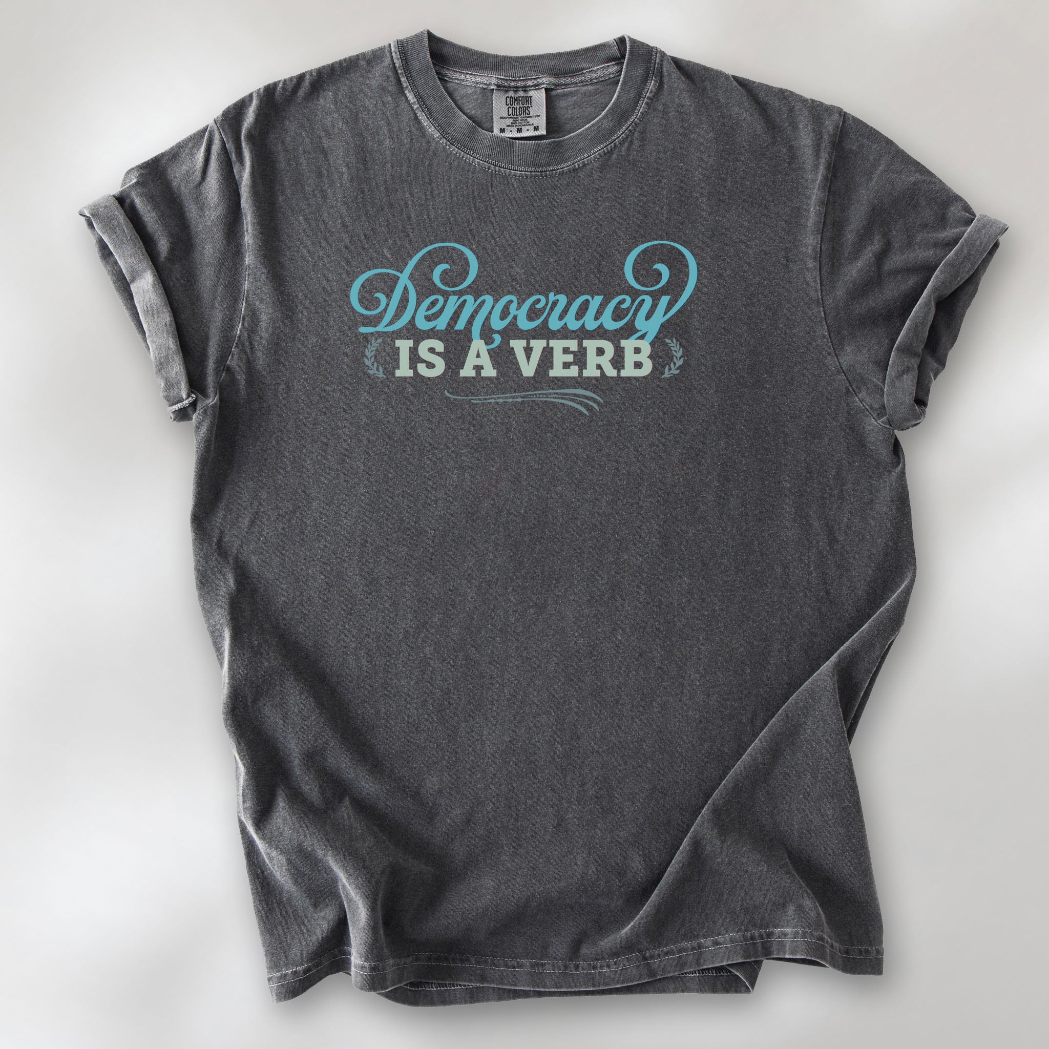 Pepper t-shirt with the phrase “Democracy Is a Verb” in decorative lettering.