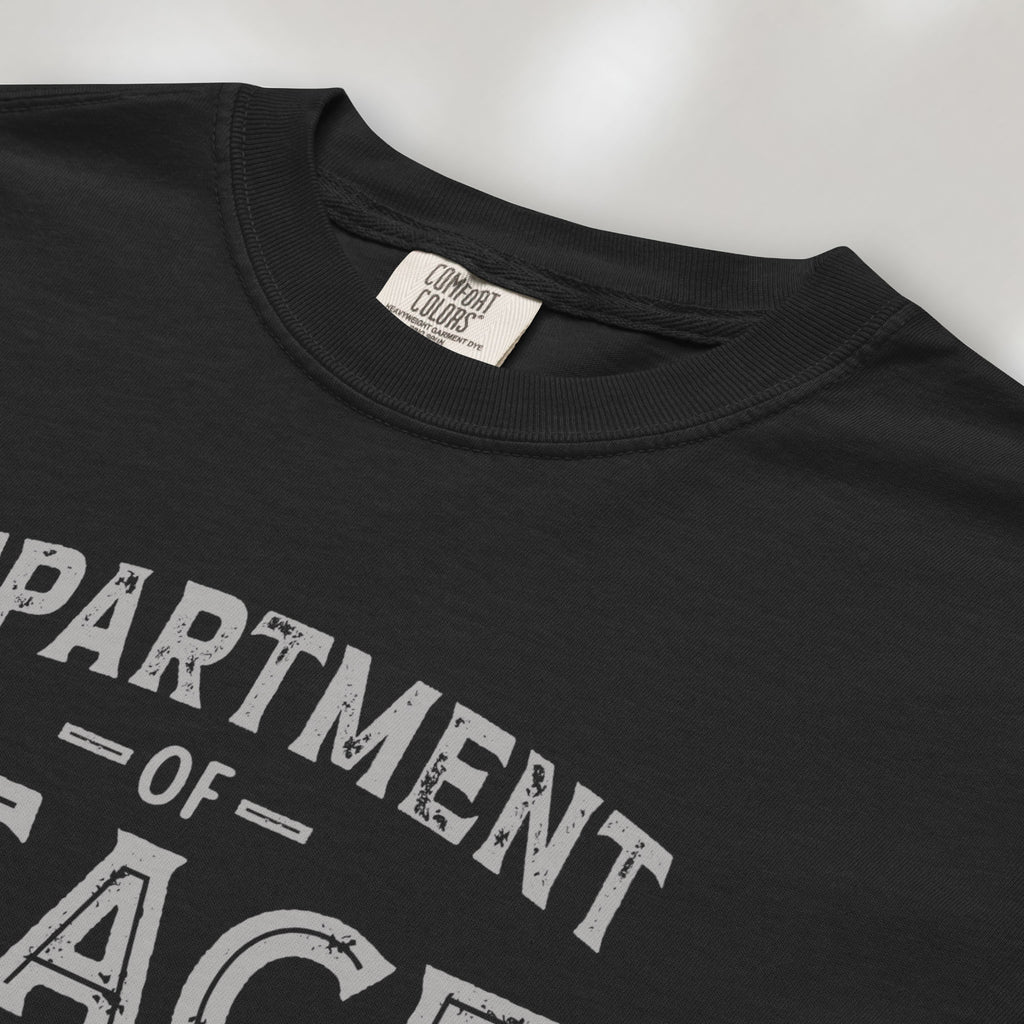 Closeup detail of black t-shirt with distressed text reading “Department of Peace — Unity is Power” in vintage style design.