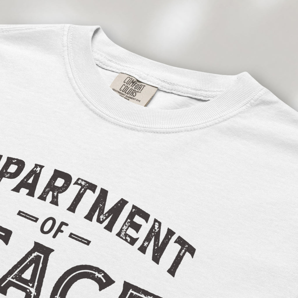 Closeup detail of white t-shirt with distressed text reading “Department of Peace — Unity is Power” in vintage style design.
