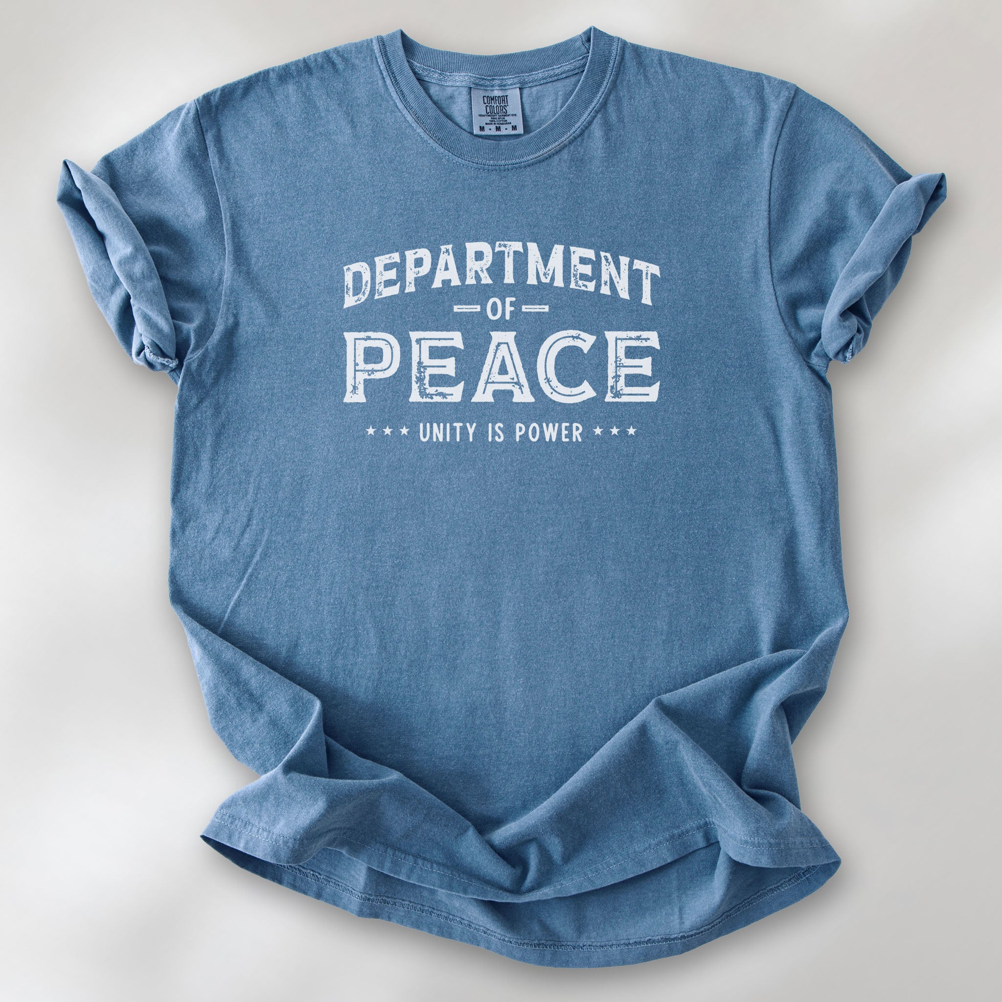 Blue jean t-shirt with distressed text reading “Department of Peace — Unity is Power” in vintage style design.