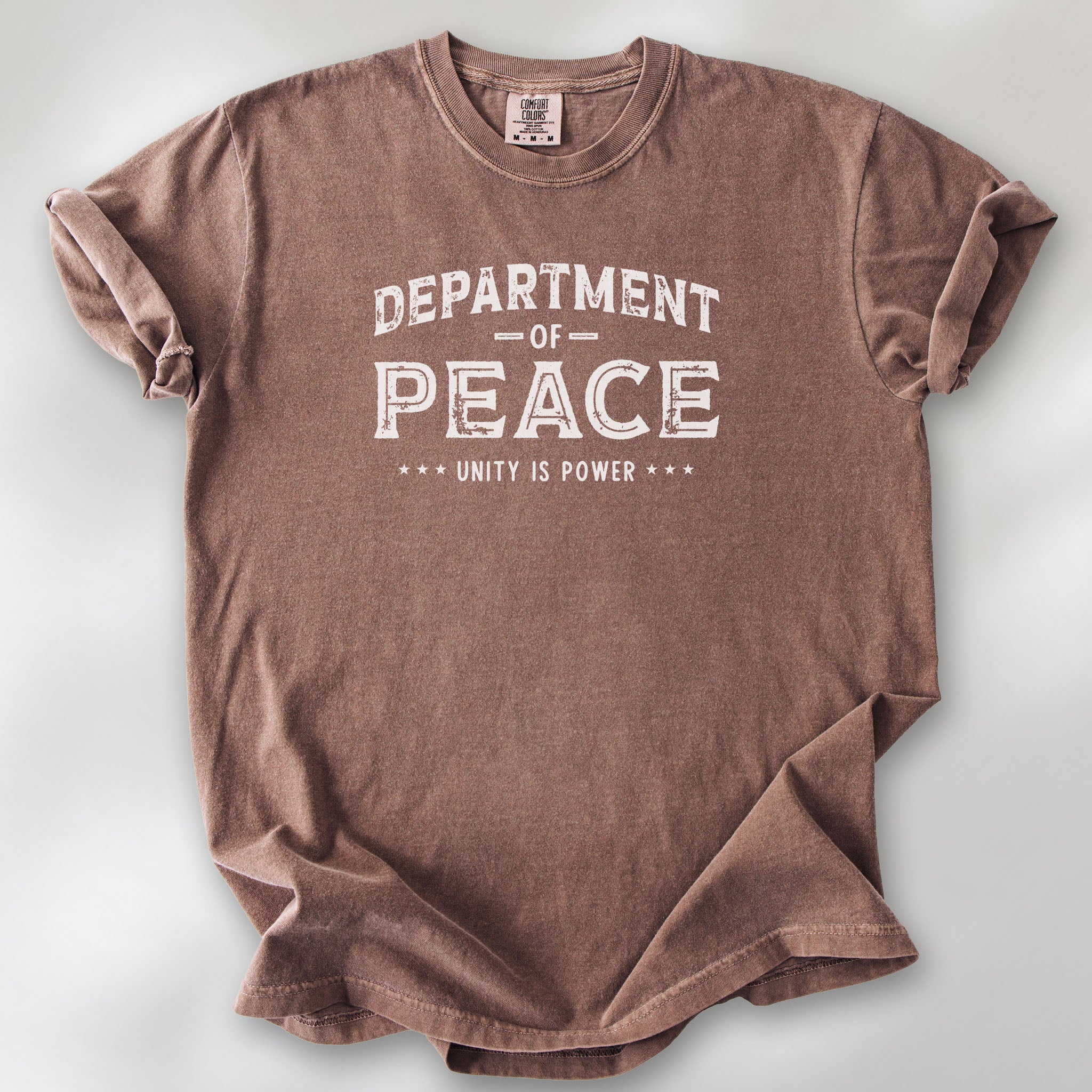 Espresso t-shirt with distressed text reading “Department of Peace — Unity is Power” in vintage style design.