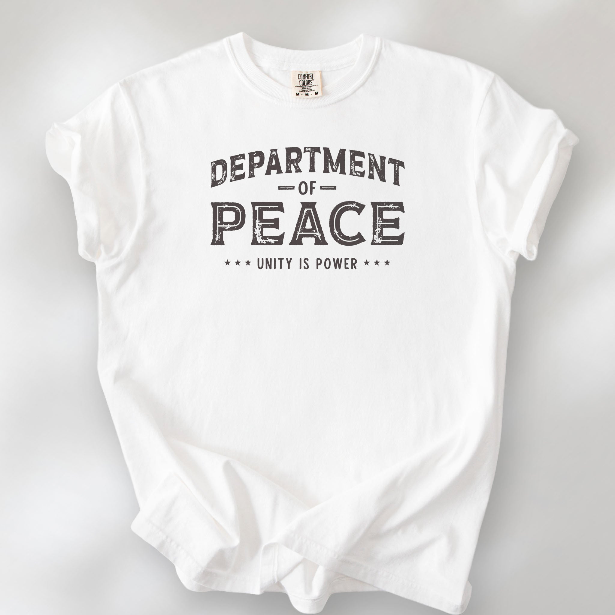 White t-shirt with distressed text reading “Department of Peace — Unity is Power” in vintage style design.