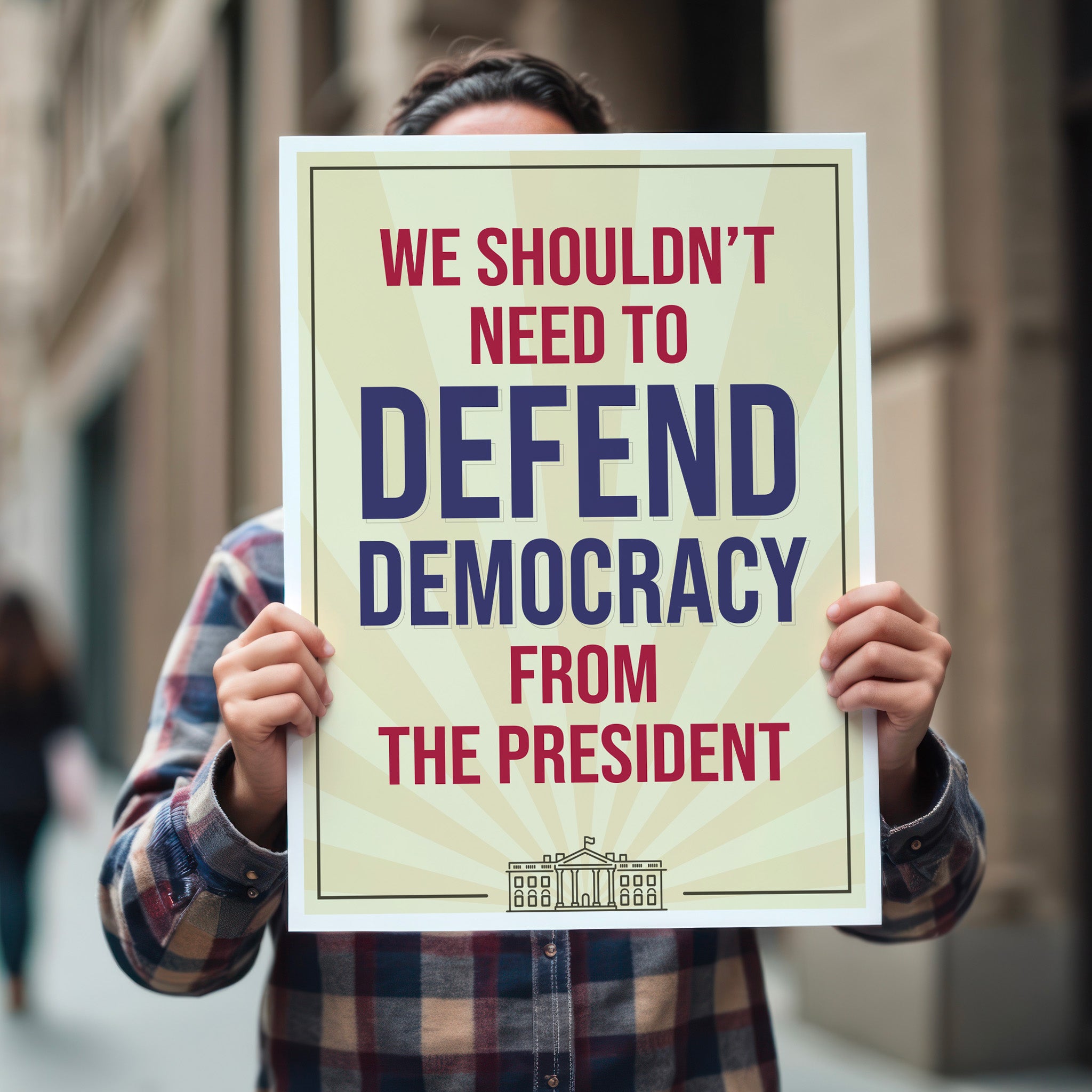 Person holding protest sign with a light gold background and red and blue text that reads "we shouldn't need to defend democracy from the president".