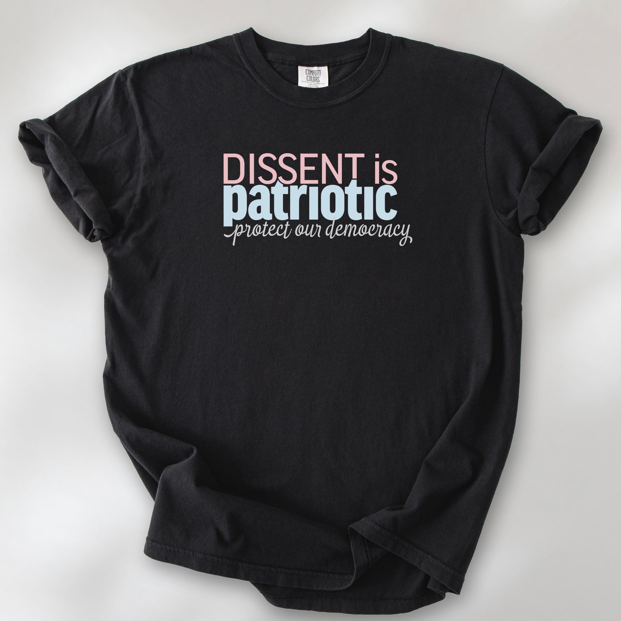 Black t-shirt with bold stylized red and blue text that reads "dissent is patriotic" with script text below that reads "protest our democracy".