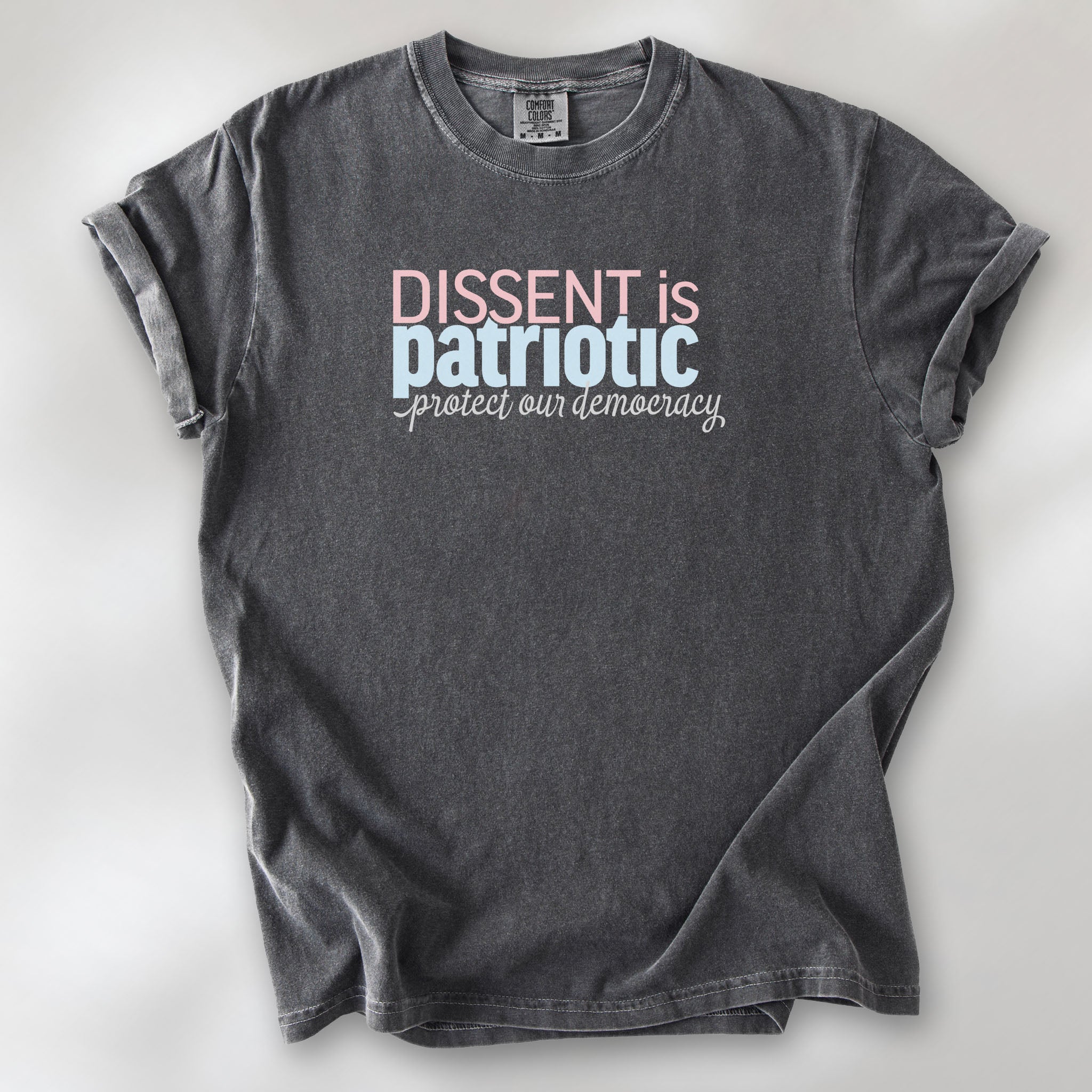 Pepper t-shirt with bold stylized red and blue text that reads "dissent is patriotic" with script text below that reads "protest our democracy".