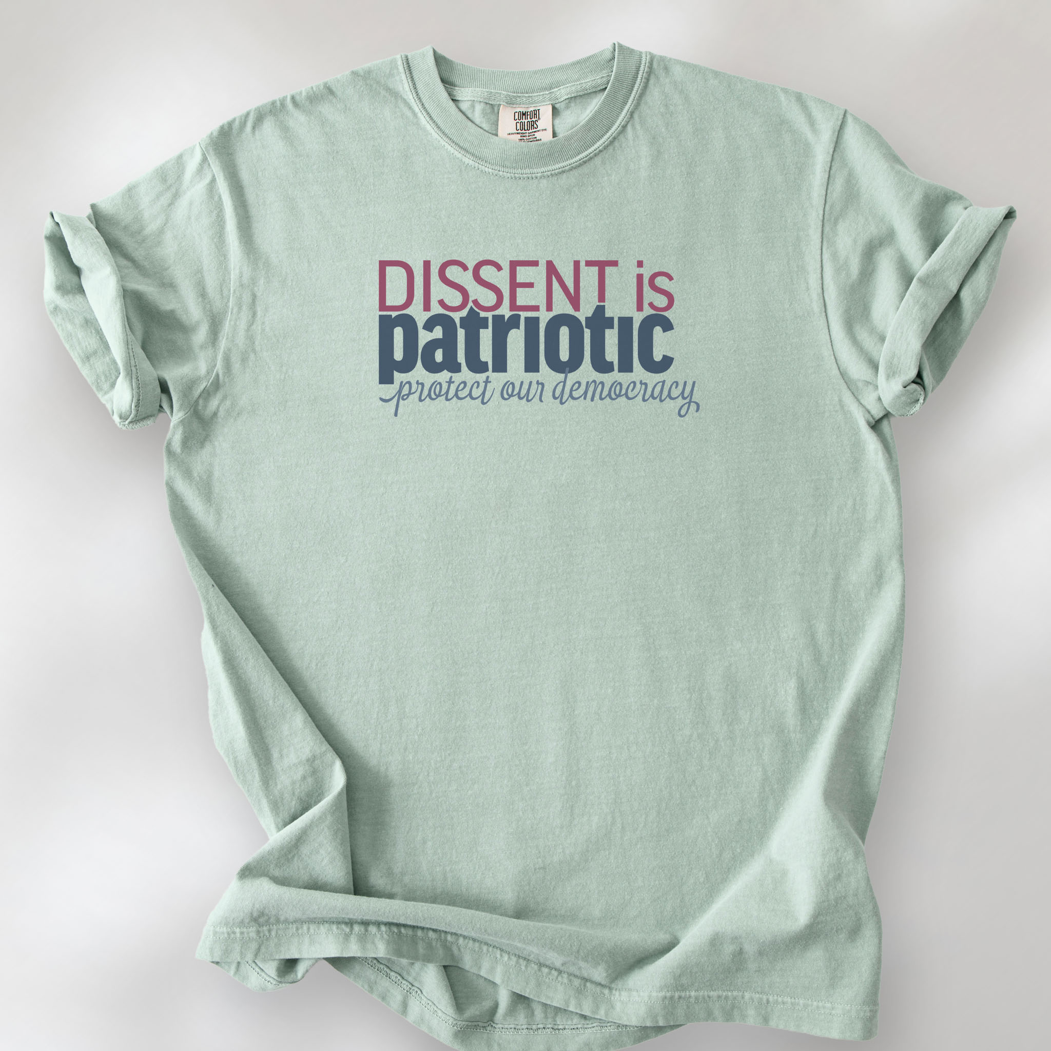 Bay unisex t-shirt with bold text reading “Dissent is Patriotic – Protect Our Democracy” in red, blue, and gray.