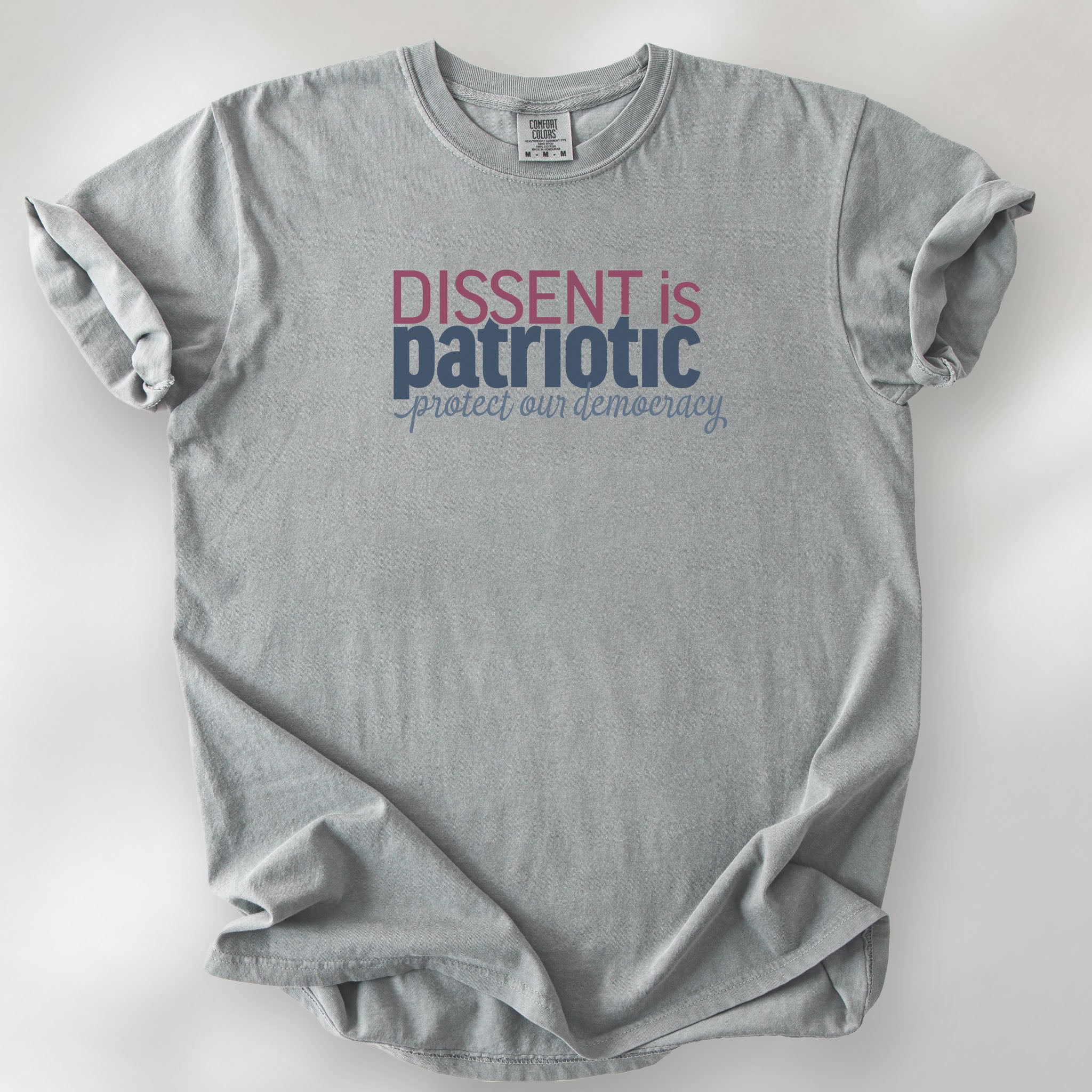 Granite unisex t-shirt with bold text reading “Dissent is Patriotic – Protect Our Democracy” in red, blue, and gray.