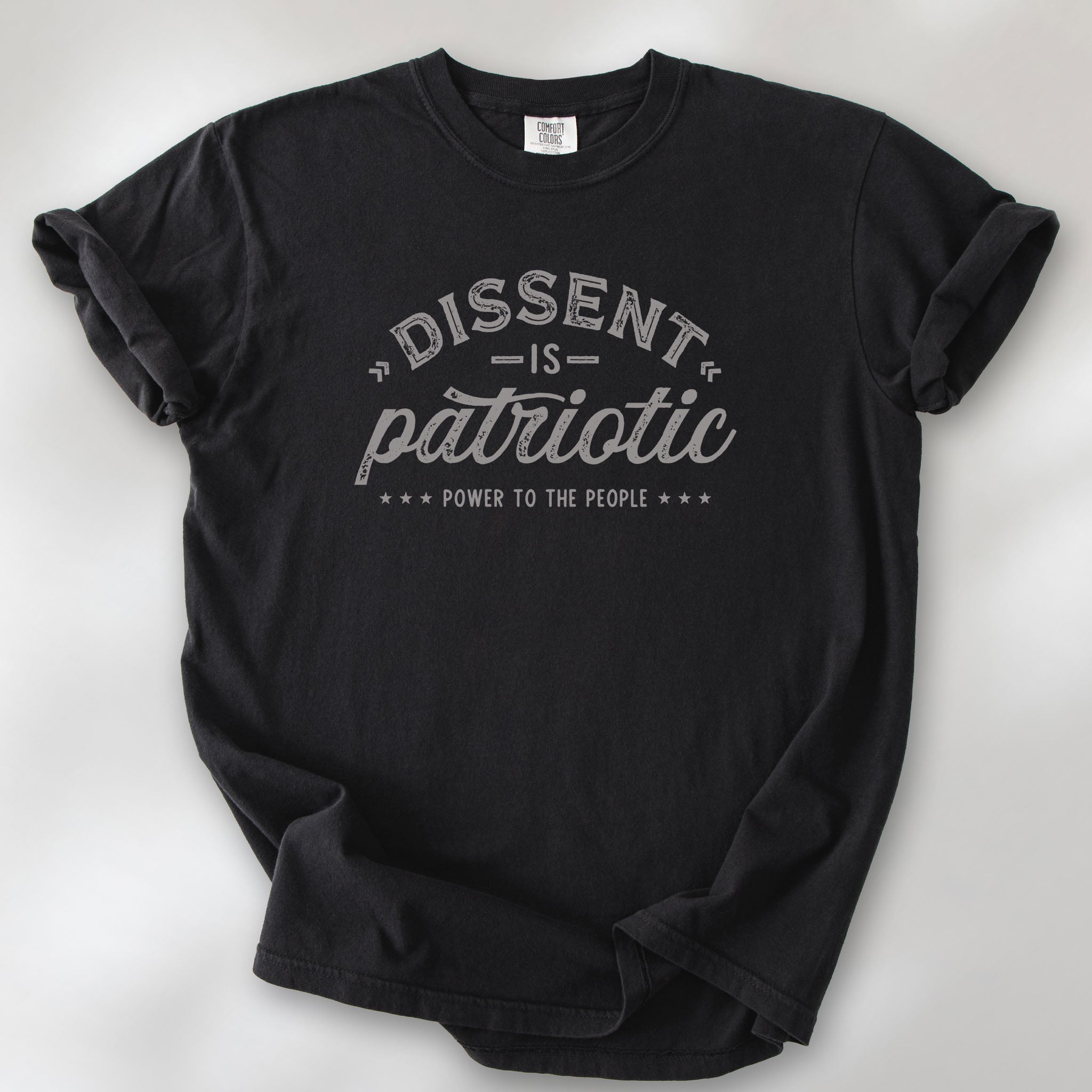 Black vintage design style shirt reading "Dissent Is Patriotic — Power To The People" in distressed typography.