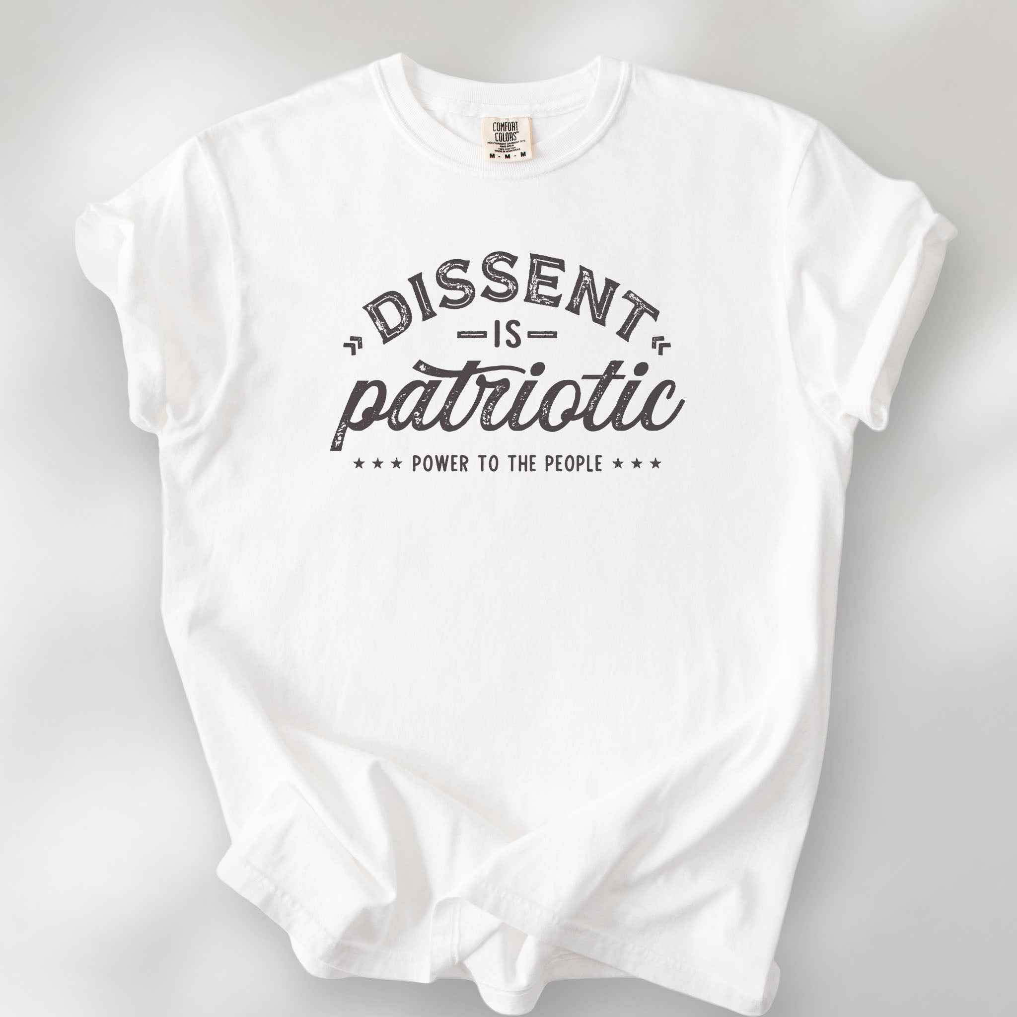 White vintage design style shirt reading "Dissent Is Patriotic — Power To The People" in distressed typography.