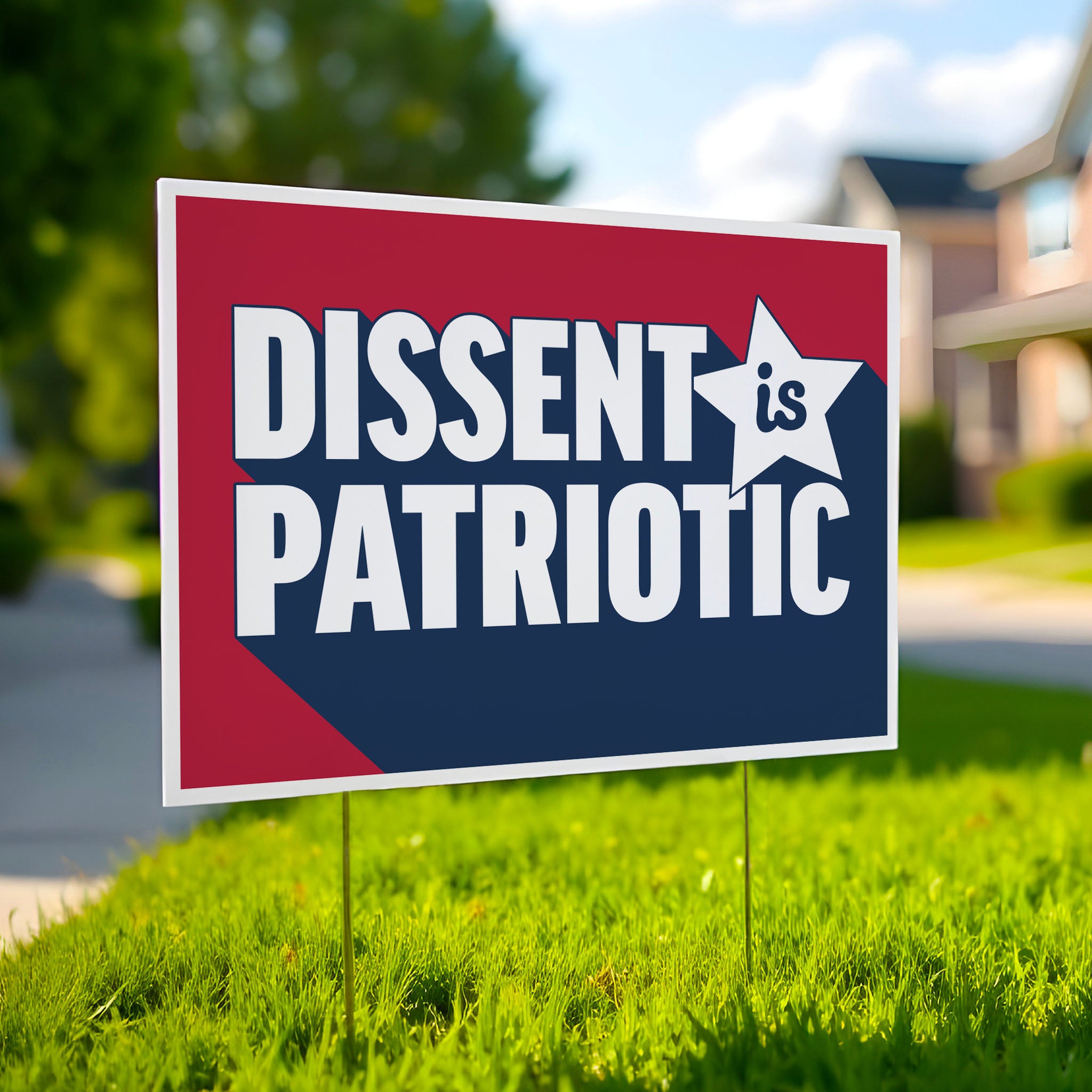 Red, white and blue yard sign with bold text that reads “Dissent is Patriotic” , planted in green lawn.