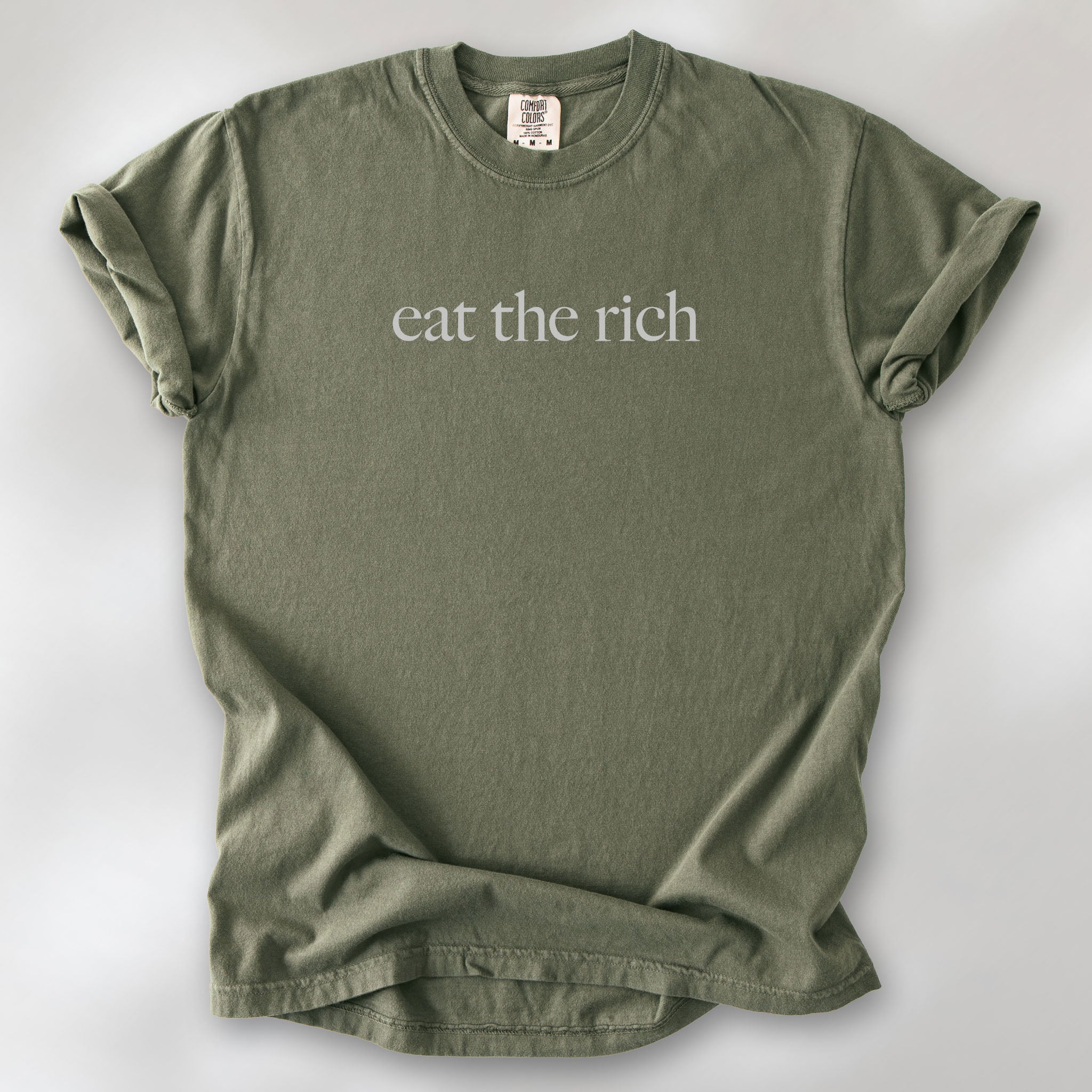 Sage t-shirt with minimalist light grey text reading “eat the rich."