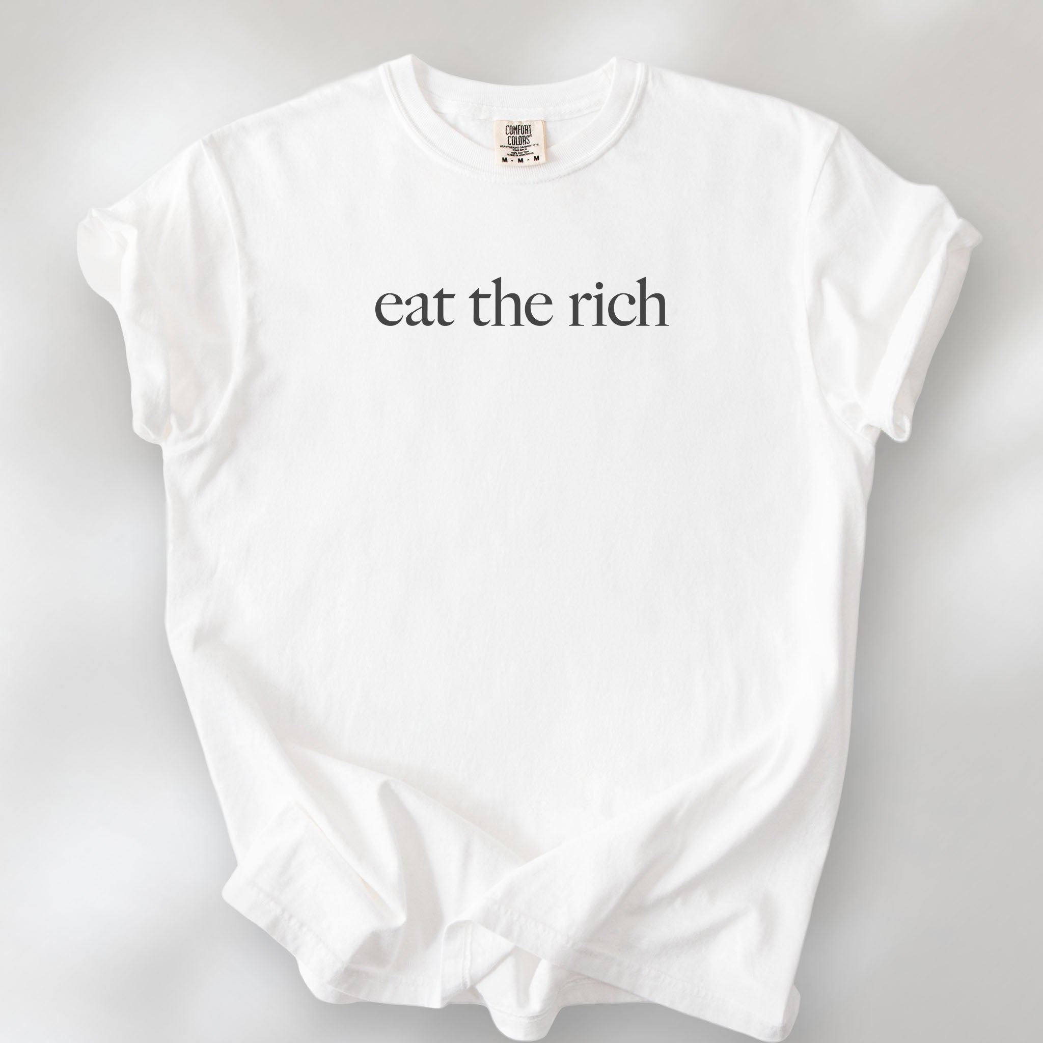 White t-shirt with minimalist dark grey text reading “eat the rich."